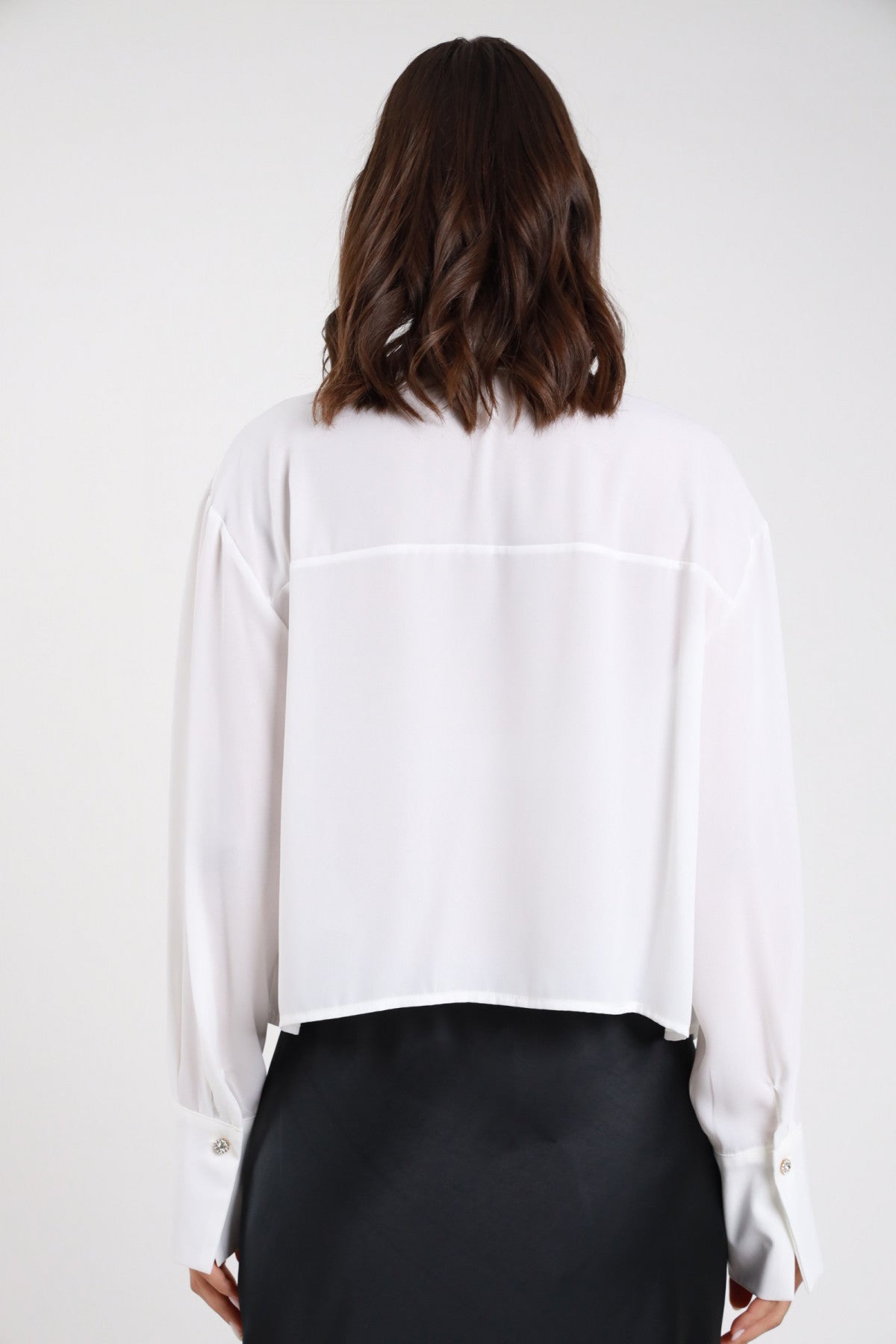 Camicia plissé bianca panna voile crepe fluido retro intera manica lunga polsino doppio bottone gioiello oversize crop orlo dritto - modella retro intera capelli castani mossi medi sfondo bianco gonna satin nera