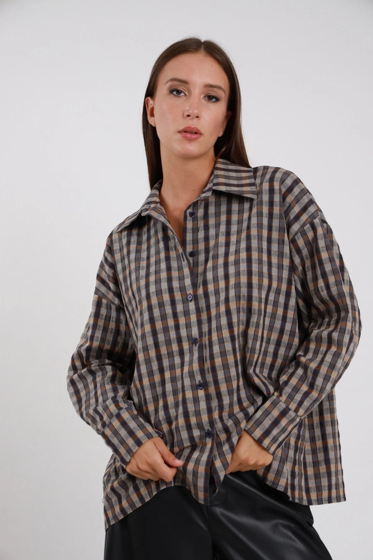 Camicia Quadri gingham grigio ardesia antracite beige oversize drop shoulder balloon colletto classico bottoni grigio scuro silhouette loose lunga busto frontale 3/4 mani tasche sguardo laterale - modella busto frontale 3/4 mani tasche jeans sguardo laterale capelli castani lisci sfondo bianco gonna ecopelle nera
