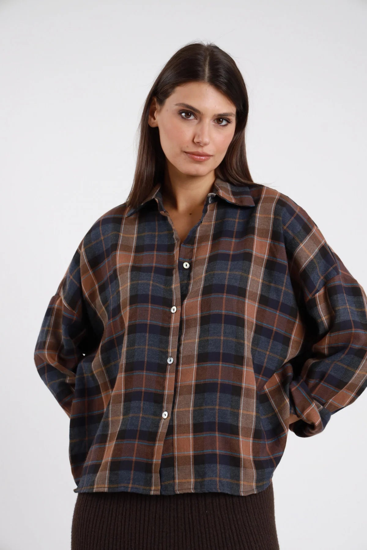 Camicia Oversize Quadri Tartan ocra senape marrone nero filo panna 57% poliestere 43% viscosa colletto aperto bottoni legno naturale tasca petto manica ampia batwing drop silhouette boxy crop - modella busto 3/4 frontale posa mano testa braccia alzate sguardo laterale alto capelli biondi mossi sfondo bianco gonna ecopelle nera