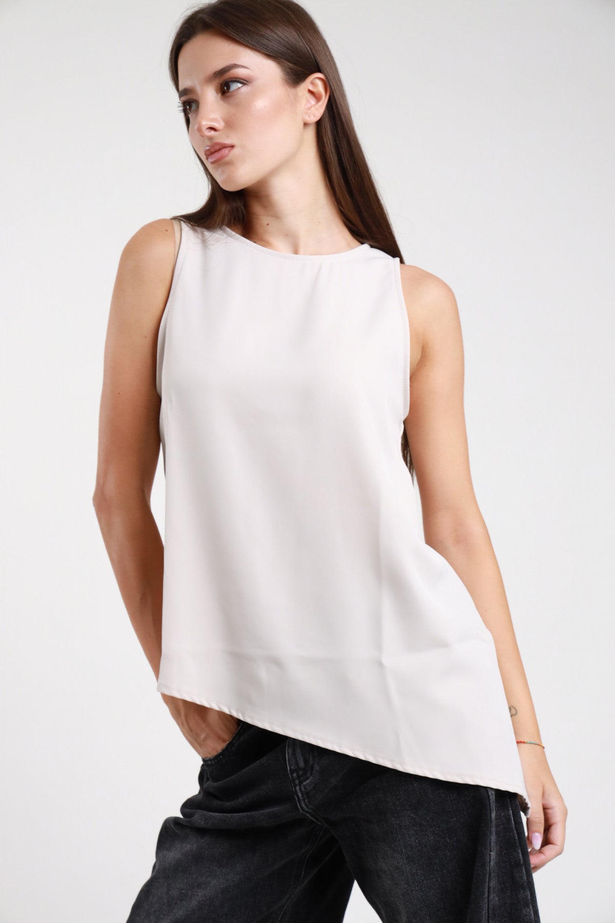 Top asimmetrico panna bianco donna spalle strutturate fondo a punta - vista tre quarti con jeans grigio scuro