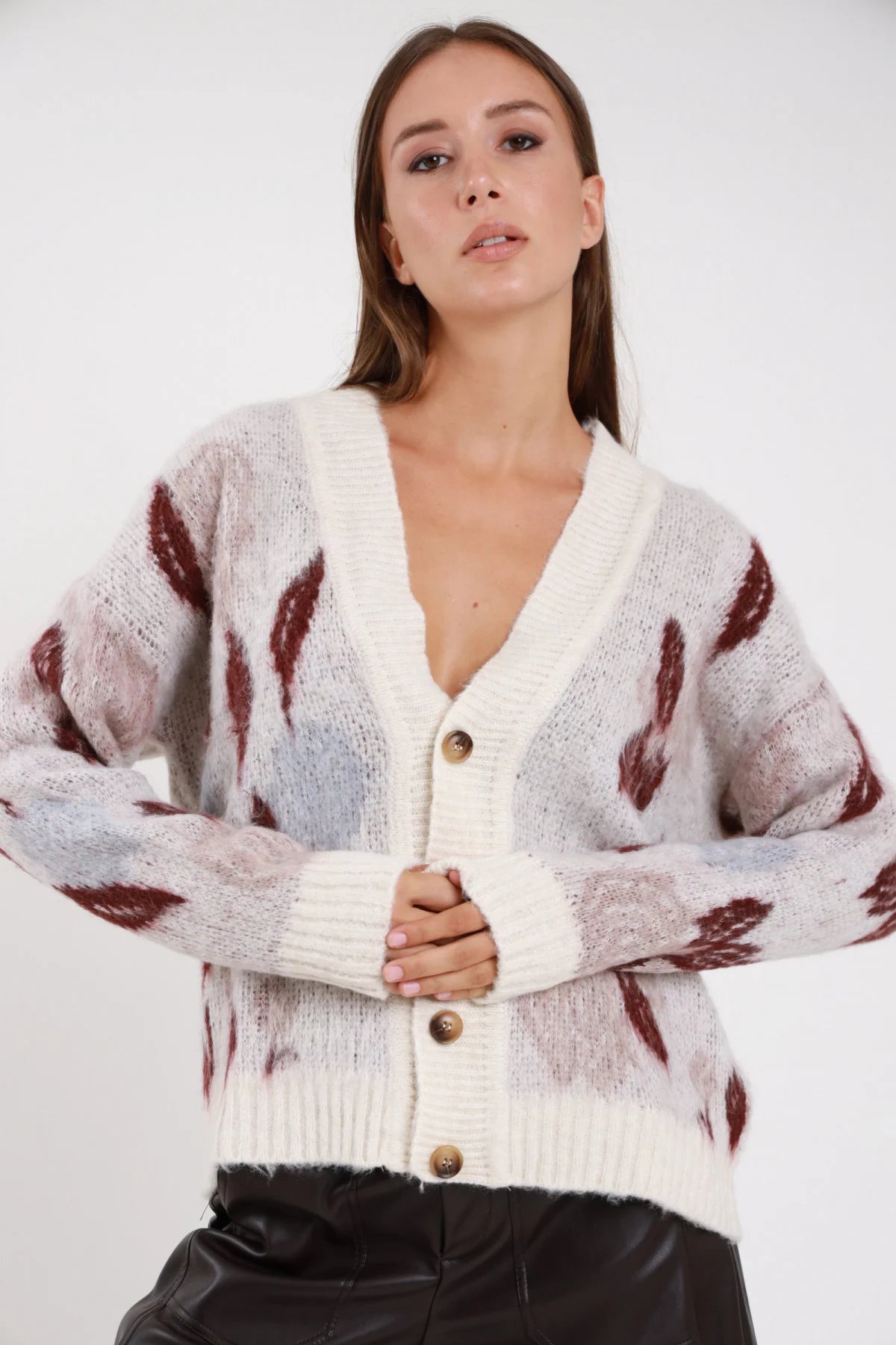 Cardigan mohair jacquard panna bianco sporco motivo astratto bordeaux bottoni dorati - modella busto frontale mani conserte gonna pelle nera capelli castani lisci