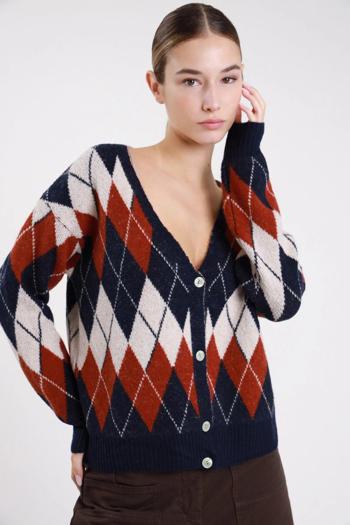 Cardigan rombi argyle blu navy terracotta panna maglia mohair - modella busto frontale mano guancia sguardo frontale con pantaloni marroni
