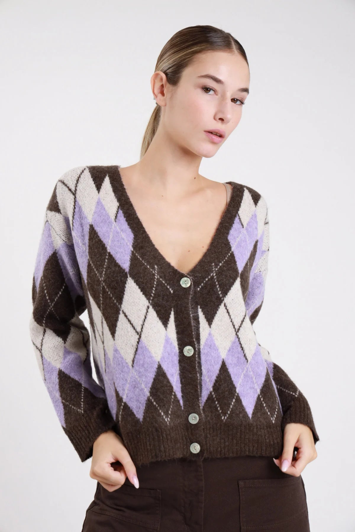 Cardigan rombi argyle cioccolato lilla panna effetto mohair - modella busto frontale mani in tasca sguardo neutro con pantaloni marroni argyle