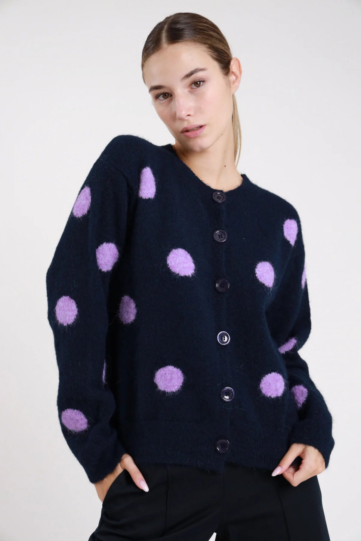 Cardigan pois navy blu notte lilla lavanda fluffy eyelash frontale tre quarti mani tasche maxi pois jacquard tridimensionali lilla girocollo abbottonatura bottoni navy dropped shoulder - modella frontale tre quarti mani tasche sguardo frontale pantaloni neri capelli castani raccolti