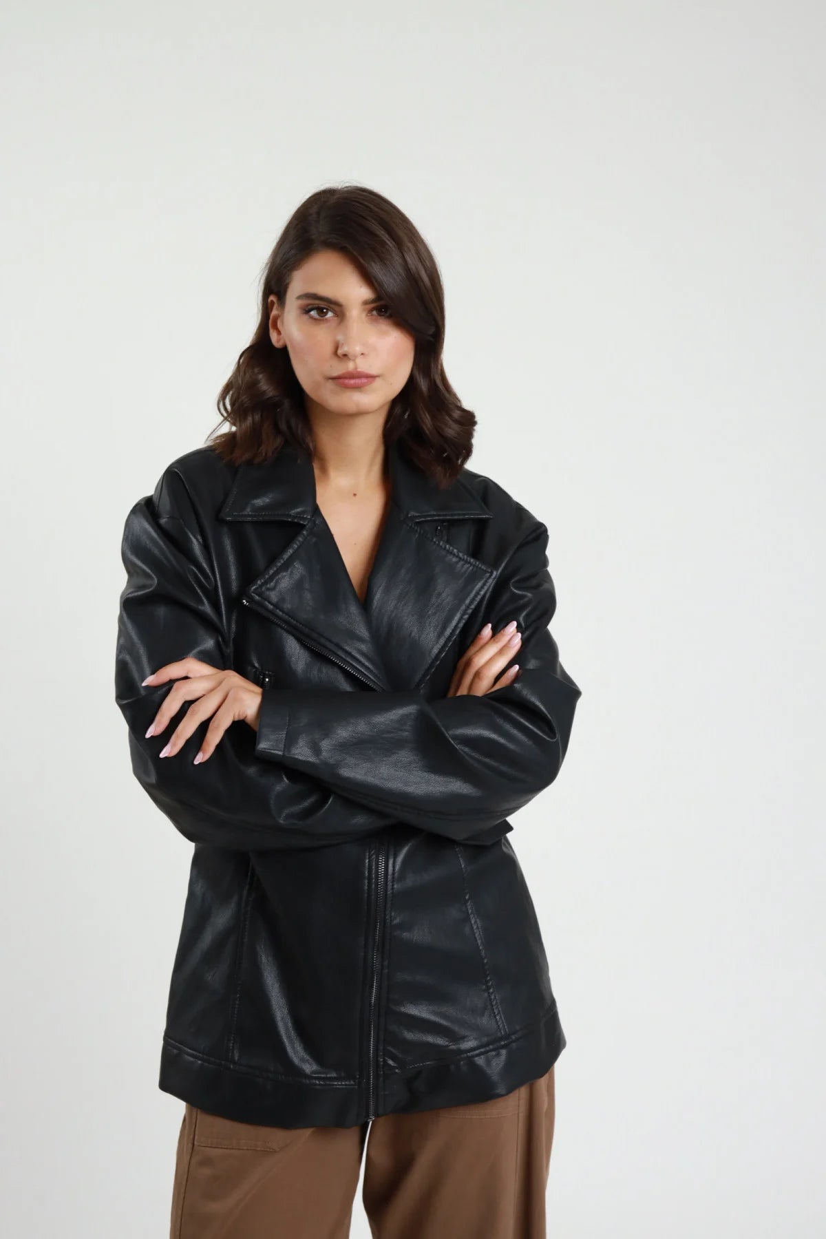 Chiodo lungo ecopelle Susy Mix nero, vista frontale della linea allungata con braccia incrociate