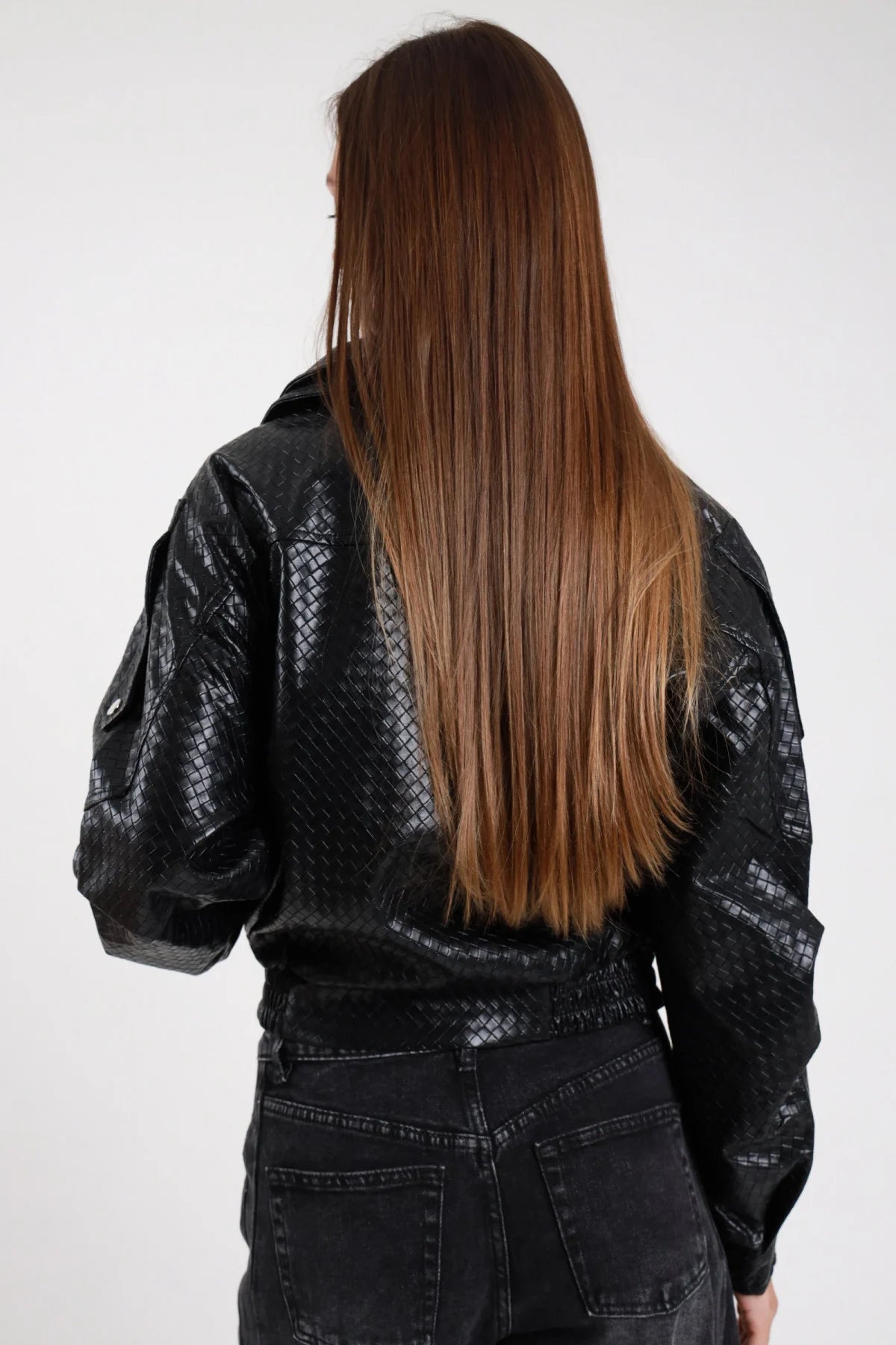 Chiodo ecopelle intrecciato rombi nero donna oversize fondo elasticizzato tasche maniche bottoni pressione - vista posteriore con jeans neri