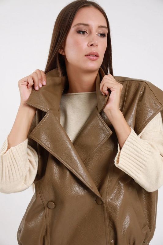 Chiodo Ecopelle Smanicato taupe kaki verde verniciata crinkled revers biker ampio doppiopetto drop shoulder vita elastica busto frontale 3/4 mani revers aperto - modella busto frontale 3/4 mani revers sguardo alto capelli castani lisci sfondo bianco maglione beige