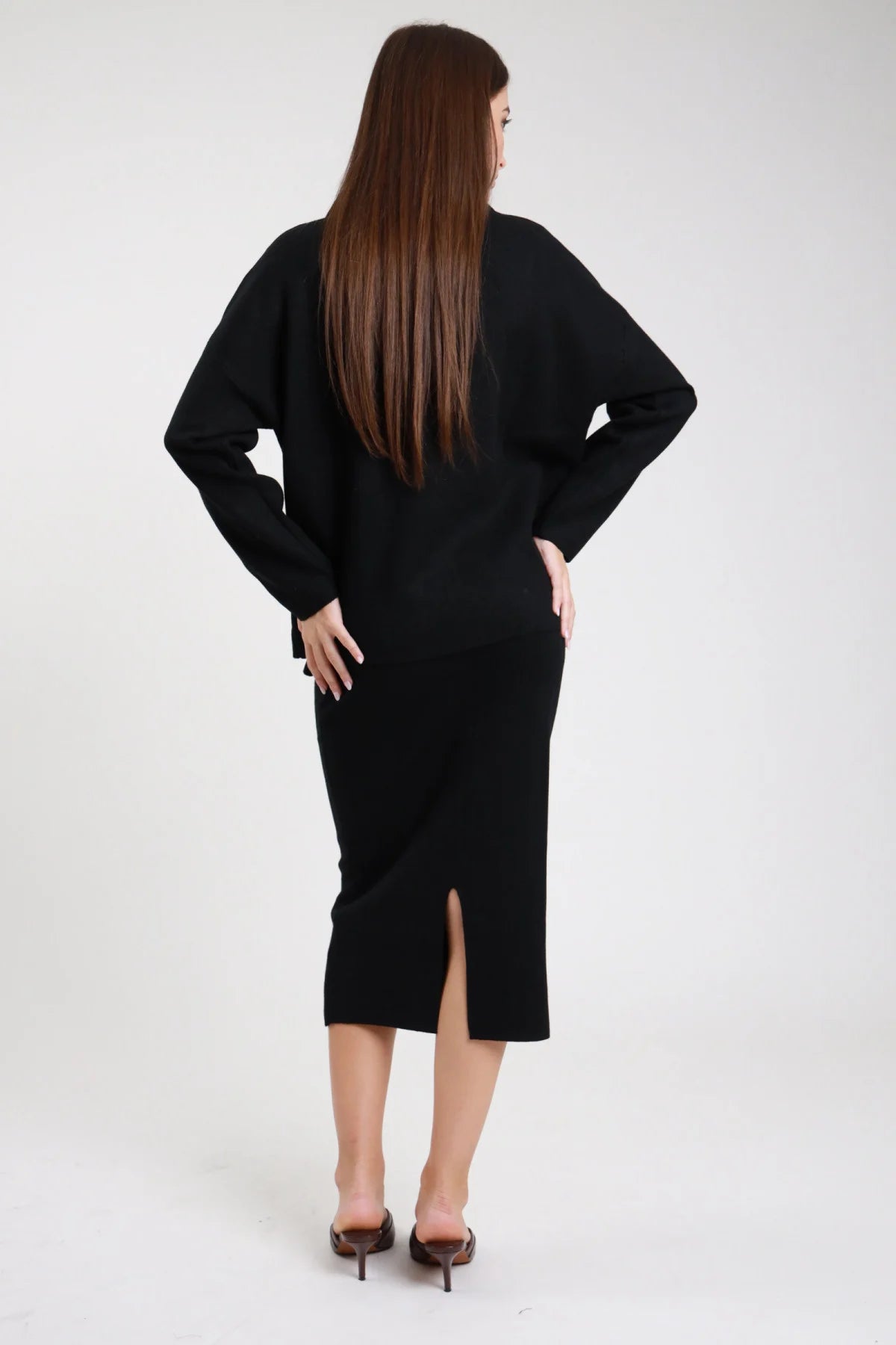 Completo coordinato gonna midi pencil coste rib maglia oversize batwing mock neck grigio perla lavanda frontale intera mano collo stivali alti neri - modella frontale intera mano collo sguardo laterale capelli castani lisci raccolti sfondo bianco stivali alti neri