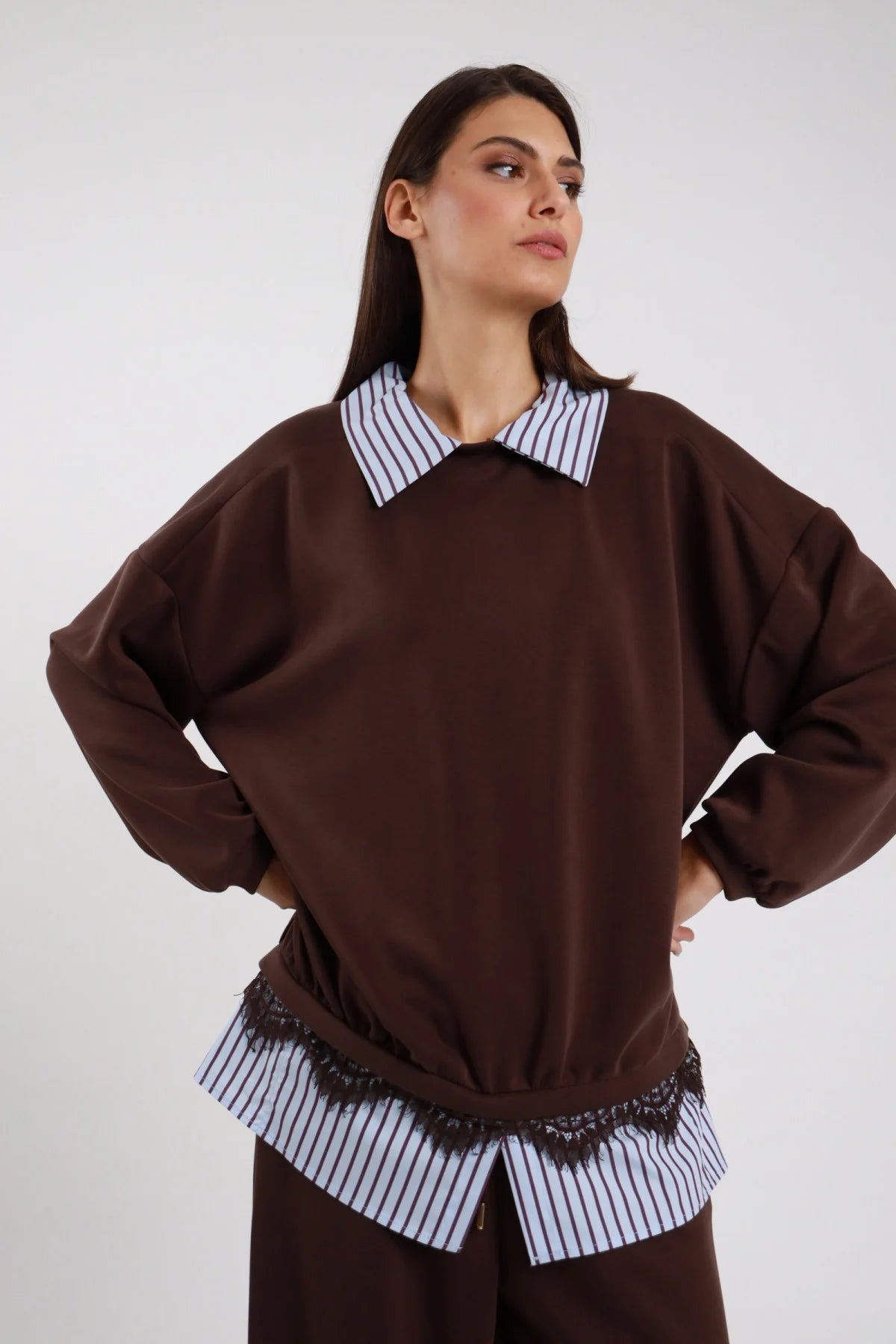 Felpa Girocollo Oversize Camicia Righe Pizzo marrone cioccolato 48% rayon colletto camicia righe bianco blu girocollo orlo camicia pizzo smerlato nero floreale elastico fondo manica raglan ampia silhouette boxy - modella busto frontale mani fianchi posa dinamica sguardo laterale alto capelli castani lisci sfondo bianco pantaloni marrone coordinati