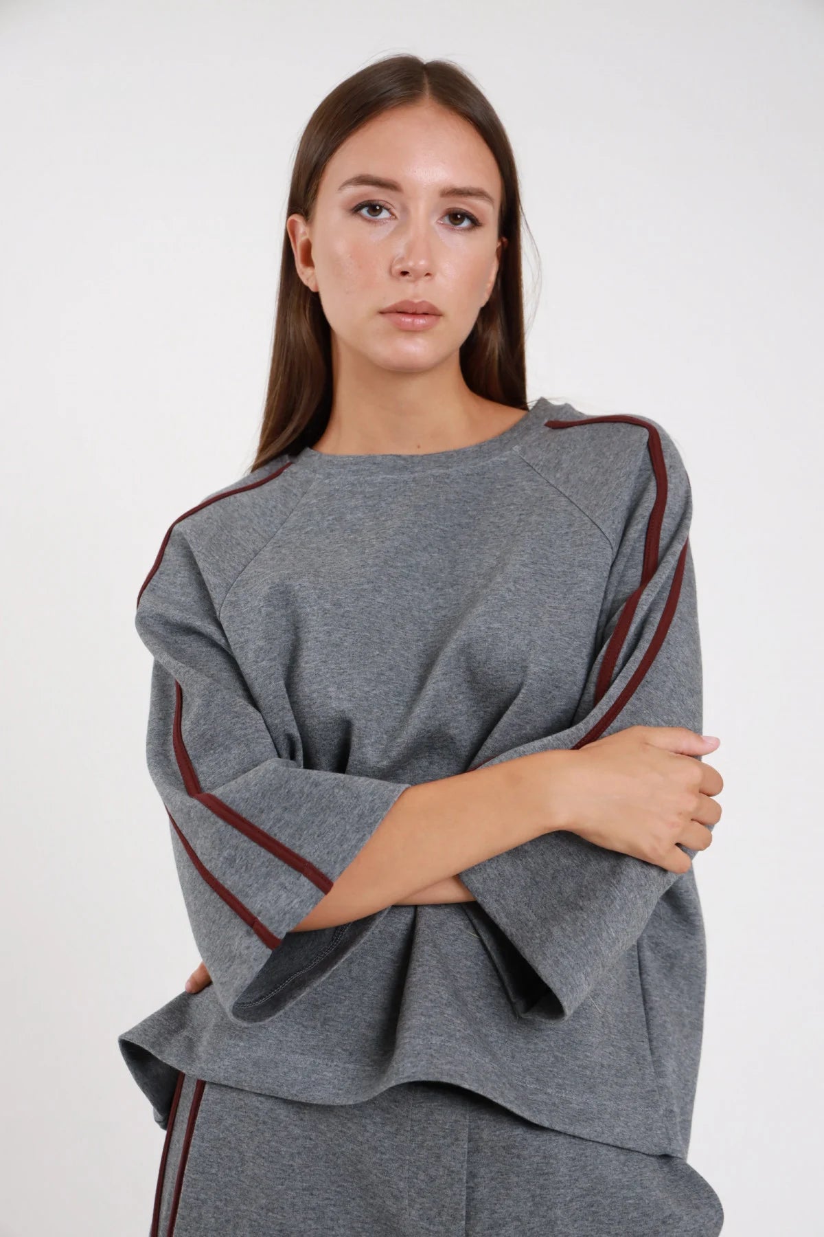 Felpa bande grigio melange frontale braccia conserte bande borgogna verticali spalla manica dropped shoulder oversize boxy - modella frontale braccia conserte sguardo frontale pantaloni grigio coordinato capelli castani lunghi lisci