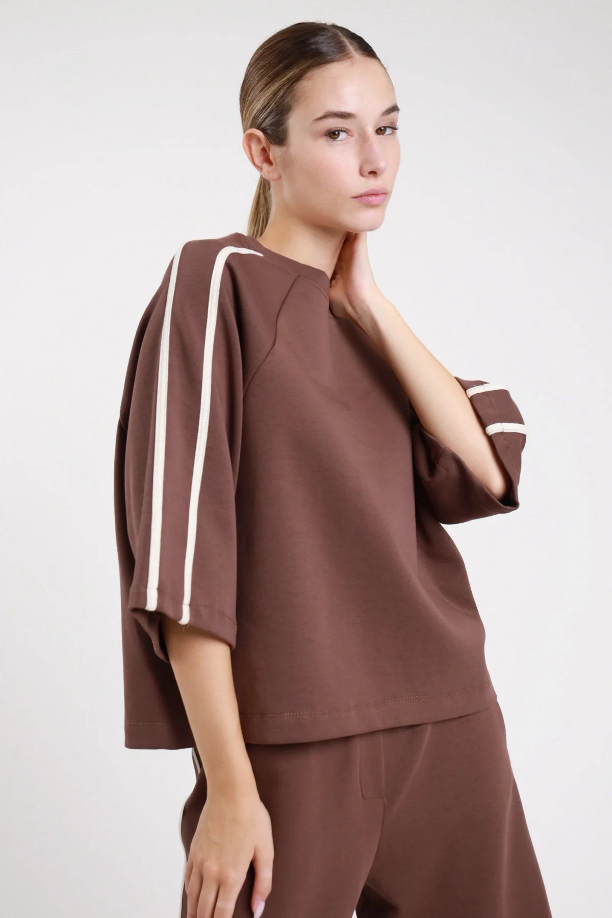 Felpa bande cioccolato moro frontale busto tre quarti bande panna ecru doppie spalla manica 3/4 dropped shoulder - modella frontale busto tre quarti mano collo sguardo frontale pantaloni cioccolato coordinato capelli castani raccolti