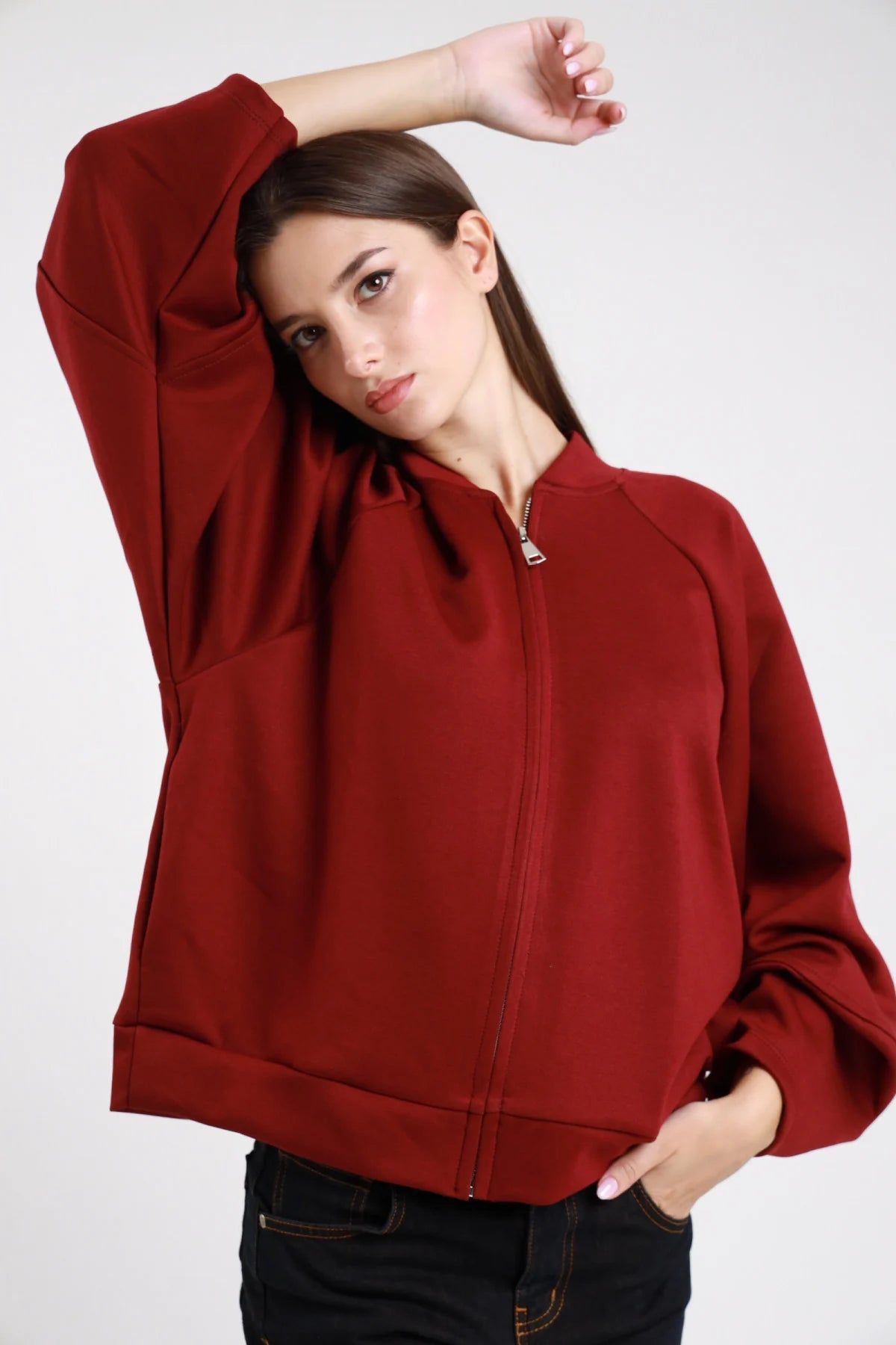 Felpa bomber bordeaux con zip dorata - modella con braccio alzato, vista frontale