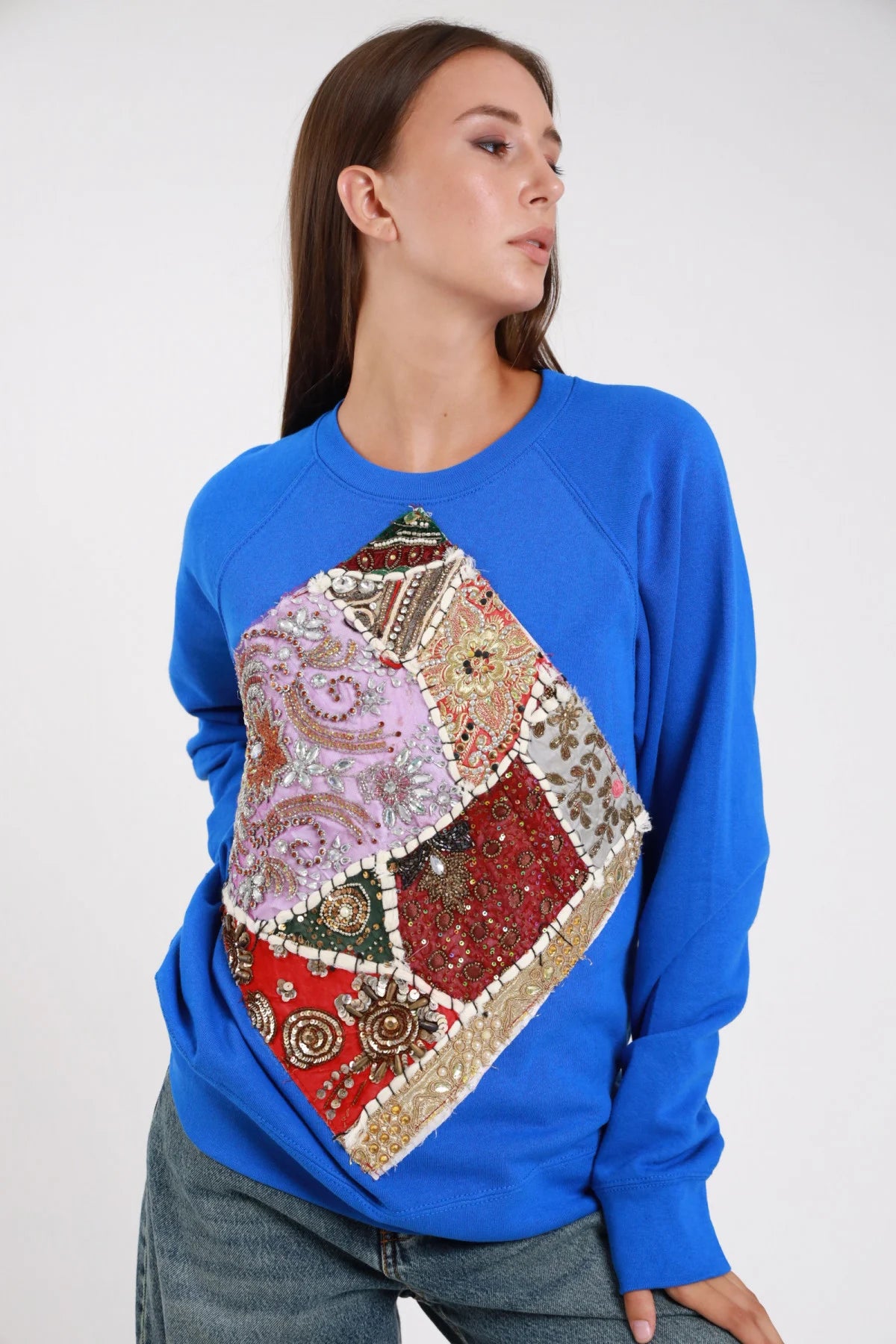 Felpa ricami patchwork blu royal cobalt frontale intera maxi applicazione rombo patchwork paisley perline - modella frontale intera sguardo laterale jeans blu capelli castani lisci mano fianco