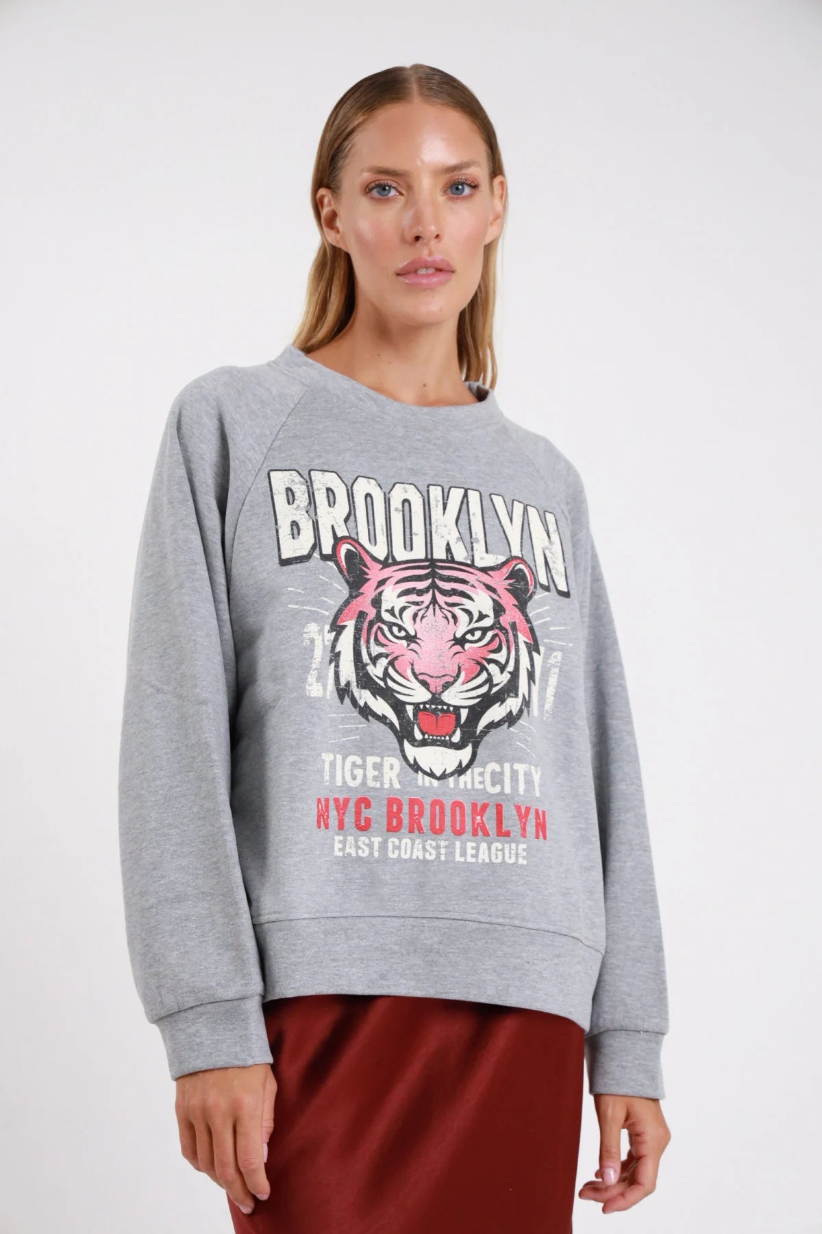 Felpa Brooklyn tiger grigio melange maxi stampa college varsity frontale busto - modella busto tre quarti sguardo frontale stampa tigre rosa gonna raso bordeaux capelli biondi raccolti