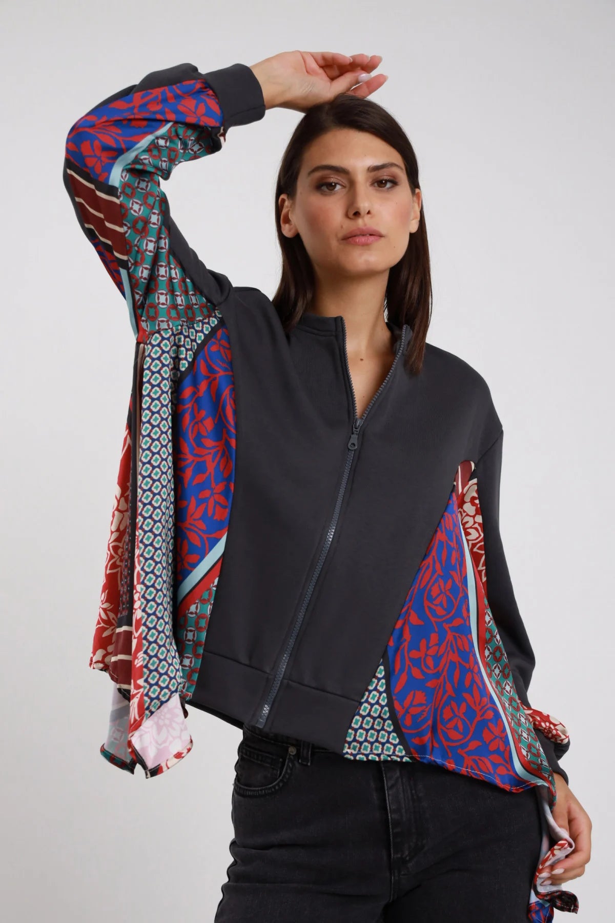 Bomber Zip Foulard Patchwork antracite grigio scuro 65% cotone collo coreana maniche interamente foulard patchwork multicolor floreale rosso geometrico blu verde inserti foulard davanti zip frontale scura polsino costina antracite - modella busto 3/4 posa mano testa sguardo laterale intenso capelli castani lisci sfondo bianco jeans nero
