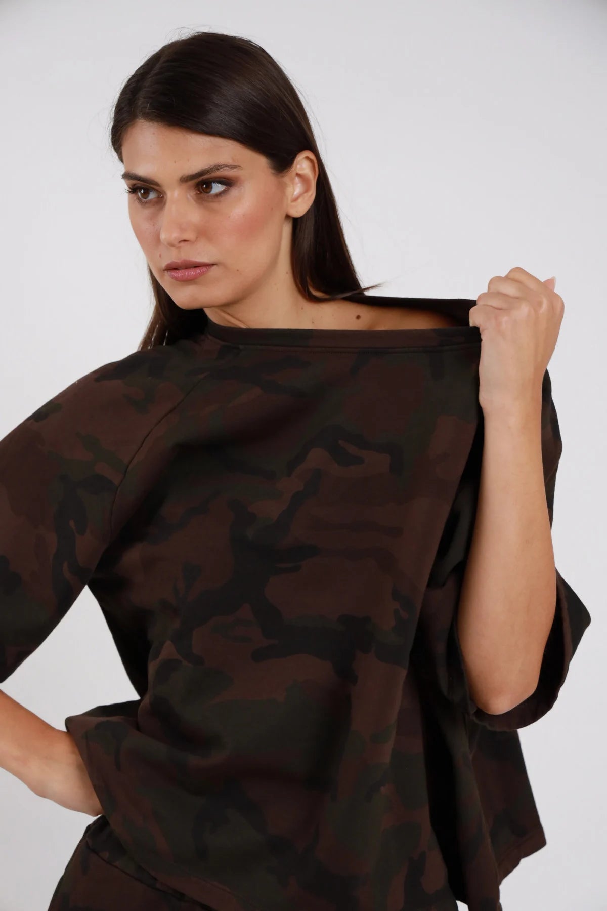 Top Over Mimetico camouflage marrone cioccolato nero sfumato 95% cotone colletto barchetta ampio cadente manica corta kimono oversize boxy - modella busto 3/4 dettaglio colletto mano destra tira colletto barchetta lateralmente sguardo laterale intenso capelli castani lisci sfondo bianco