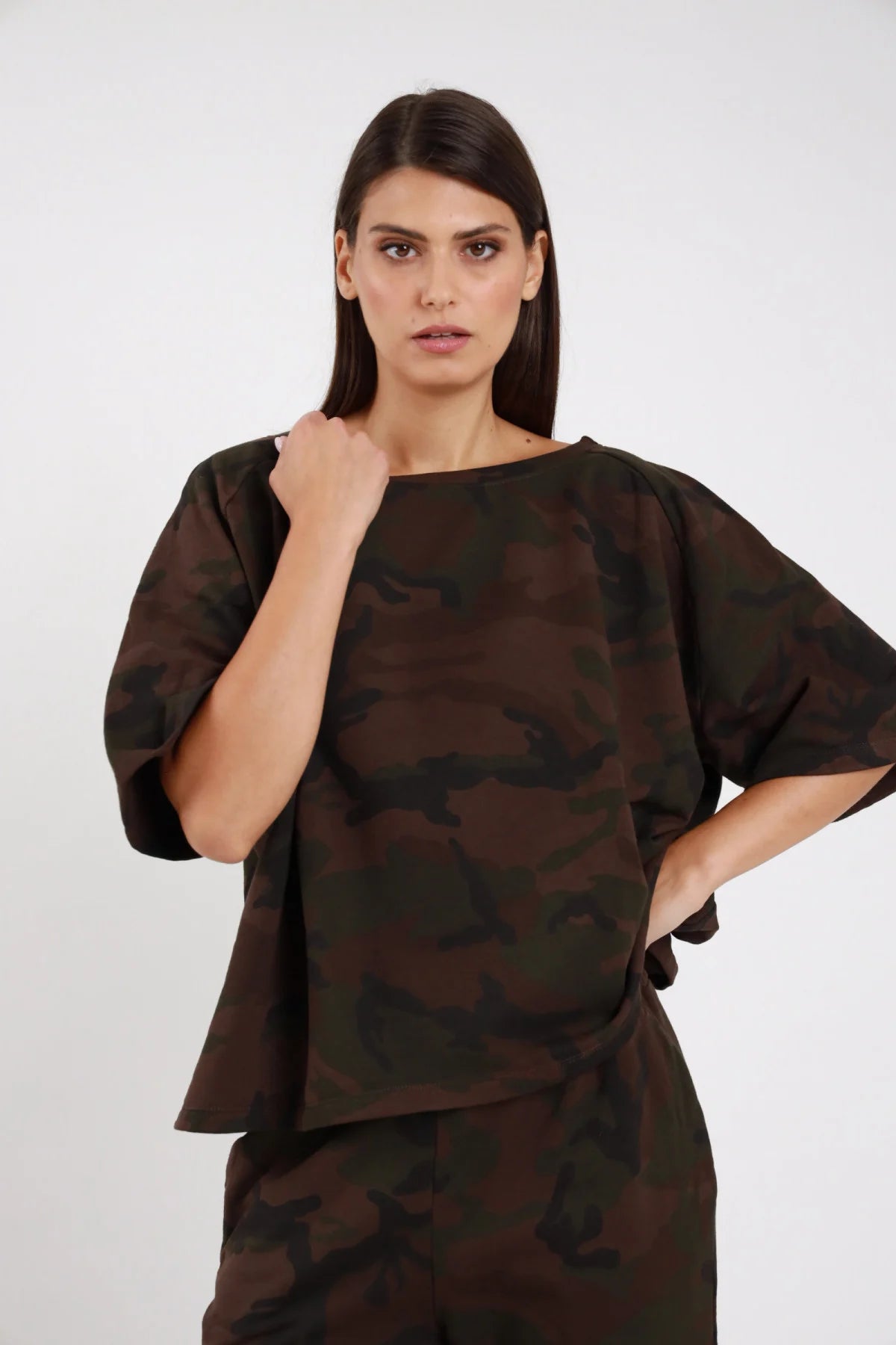 Top Over Mimetico camouflage marrone cioccolato nero sfumato 95% cotone colletto barchetta cadente manica corta kimono silhouette boxy oversize frontale busto posa mano petto sguardo frontale - modella busto frontale posa mano petto sguardo frontale capelli castani lisci sfondo bianco pantalone ovetto mimetico coordinato