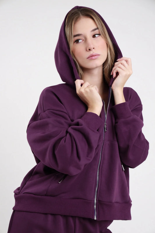 Felpa Zip SMX Limited Edition viola melanzana 65% cotone french terry hoodie cappuccio ampio coulisse argento zip frontale completa tasche zip laterali manica balloon polsino costina bordo costina oversize busto 3/4 mani cappuccio - modella busto 3/4 mani coulisse cappuccio sguardo laterale alto capelli biondi chiari sfondo bianco pantalone wide leg viola coordinato abbinato