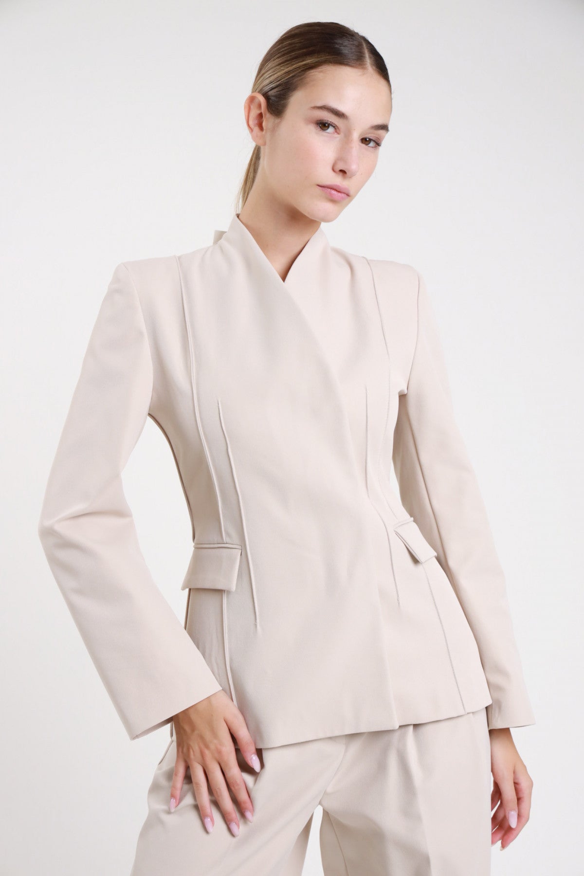 Blazer asimmetrico beige sabbia nervature collo kimono - modella busto tre quarti con cintura laterale e pantaloni beige coordinati