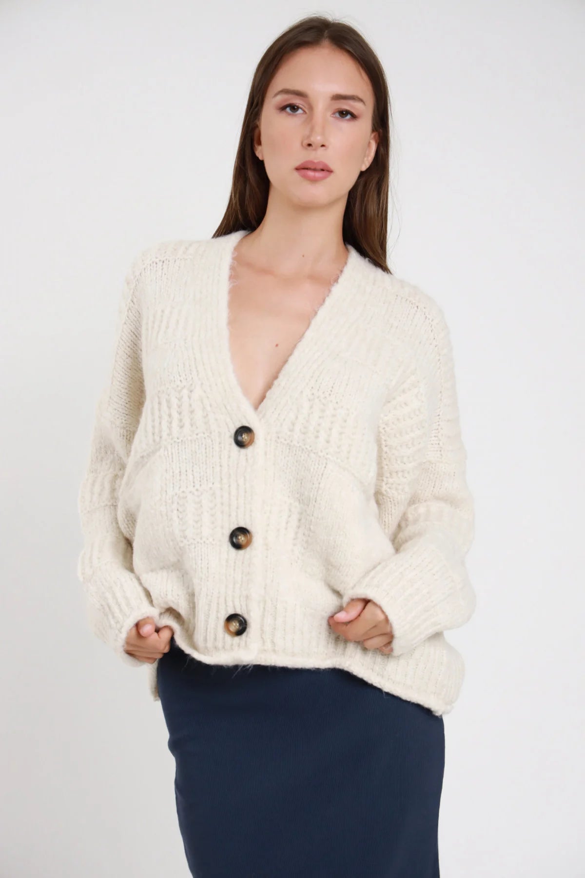 Cardigan over maglia eyelash fluffy trecce cable rosa cipria blush frontale busto mani vita scollo V bordo sfrangiato 3 bottoni tortoise tasche toppa corpo oversize manica dropped shoulder balloon - modella frontale busto mani vita sguardo frontale intenso pantaloni ecopelle nero capelli castani lisci