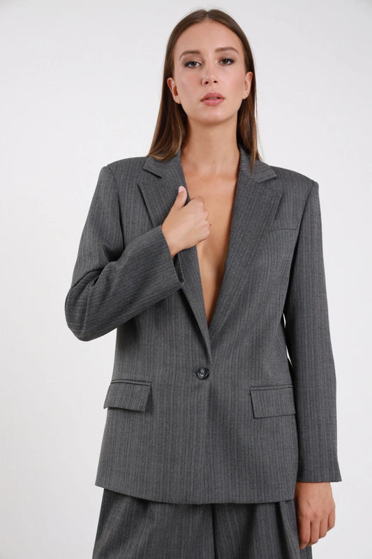 Blazer Spinato herringbone grigio antracite lurex revers classico monobottone tasche pattina spalle strutturate busto frontale 3/4 mano colletto aperto - modella busto frontale 3/4 mano colletto sguardo camera capelli castani lisci sfondo bianco bermuda grigio spinato