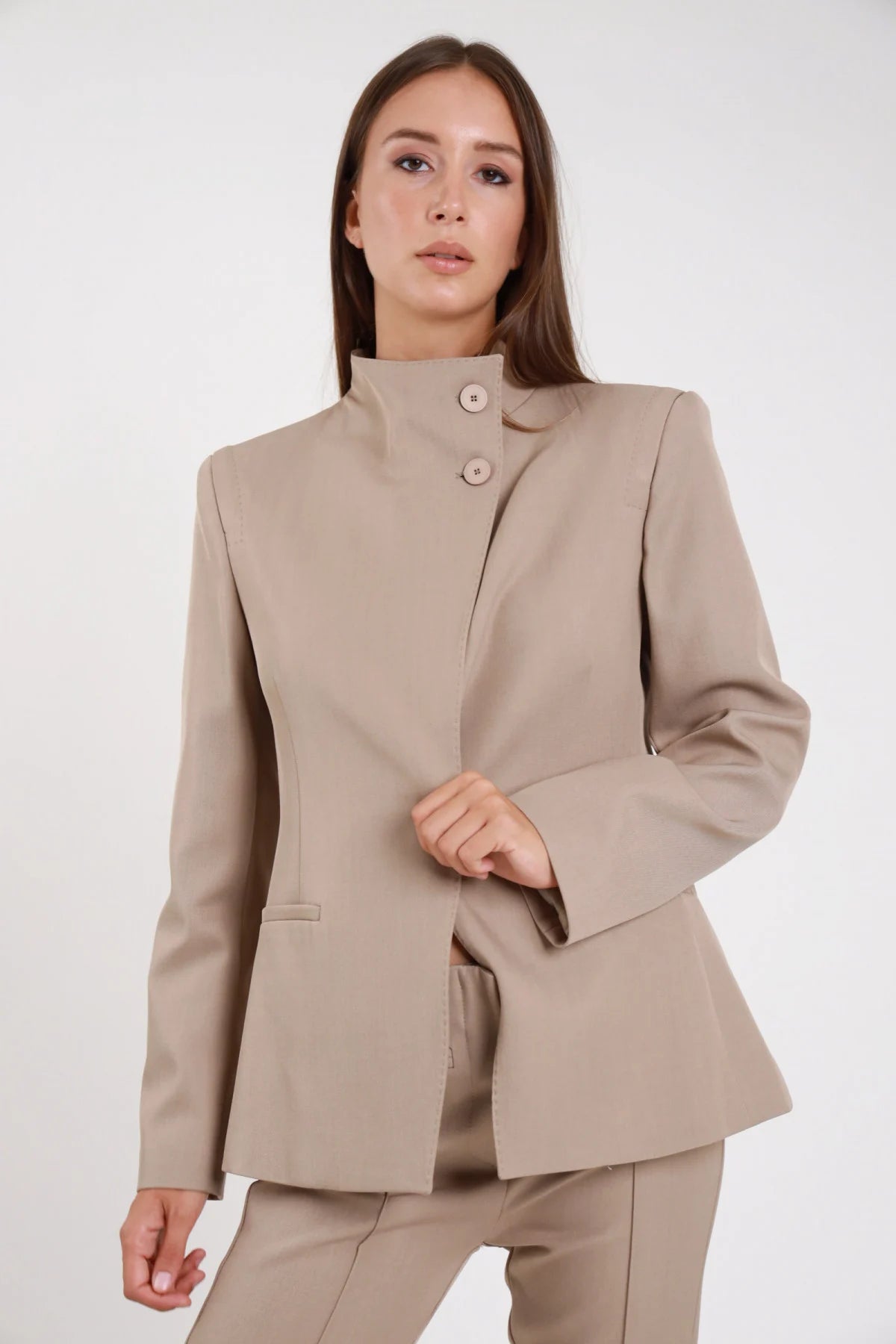 Blazer chiusura asimmetrica nero colletto coreana doppio bottone spalle strutturate - modella busto frontale mani lungo fianchi sguardo frontale pantalone abbinato nero capelli castani lisci