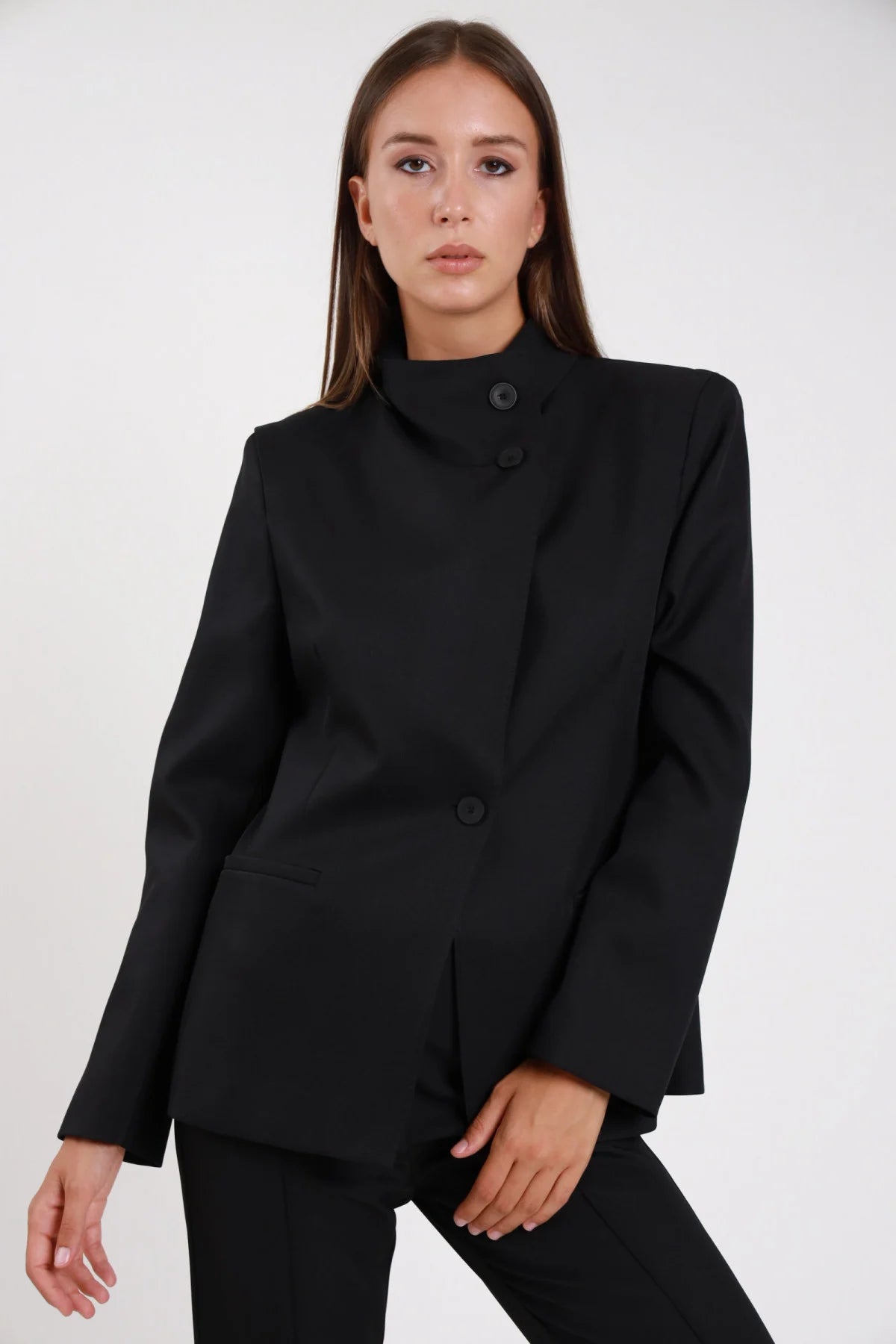 Blazer chiusura asimmetrica navy blu scuro sartoriale stretch polsino ampio - modella busto frontale mano sul fianco sguardo laterale pantalone abbinato navy capelli biondi ondulati