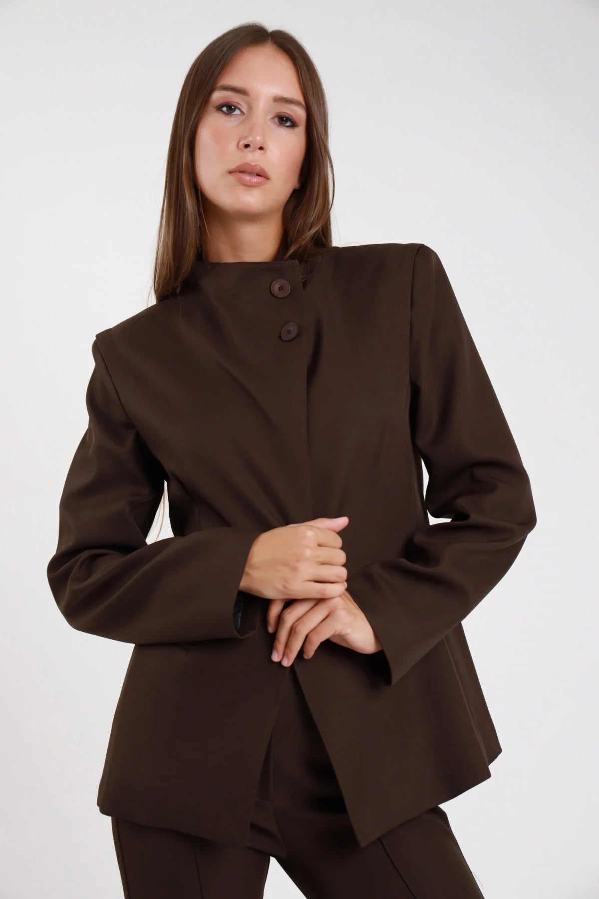 Blazer asimmetrico cioccolato marrone sartoriale tecnico stretch tre quarti dinamico - modella busto tre quarti mano in testa sguardo basso aperto pantalone abbinato capelli castani