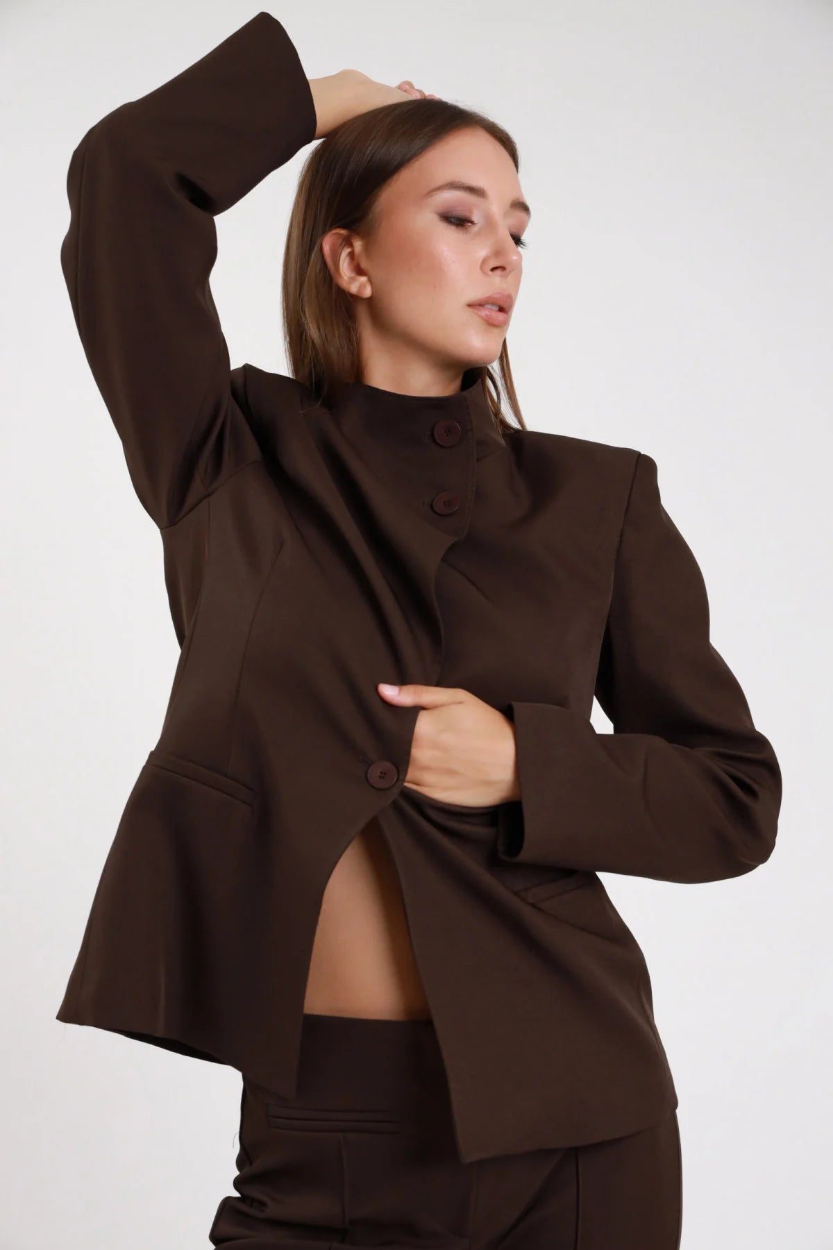 Blazer chiusura asimmetrica cioccolato marrone dettaglio bottone asimmetrico polsino ampio - modella busto ravvicinato tre quarti sguardo basso capelli castani lisci pantalone abbinato