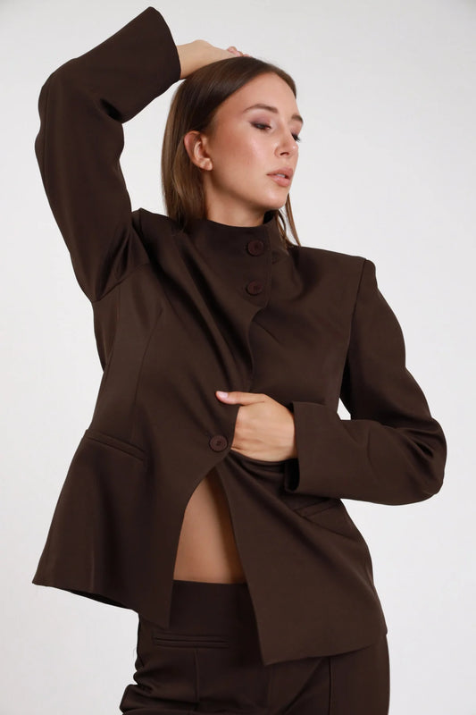 Blazer chiusura asimmetrica cioccolato marrone dettaglio bottone asimmetrico polsino ampio - modella busto ravvicinato tre quarti sguardo basso capelli castani lisci pantalone abbinato