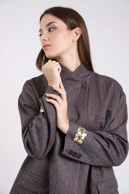 Blazer spigato herringbone grigio antracite marrone scuro lurex bronzo ramato dettaglio busto laterale mano mento collo alto funnel neck abbottonatura asimmetrica singolo bottone scuro manica balloon bishop bracciale gioiello floreale foglia oro polso - modella dettaglio busto laterale mano mento sguardo laterale alto capelli castani lisci sfondo bianco
