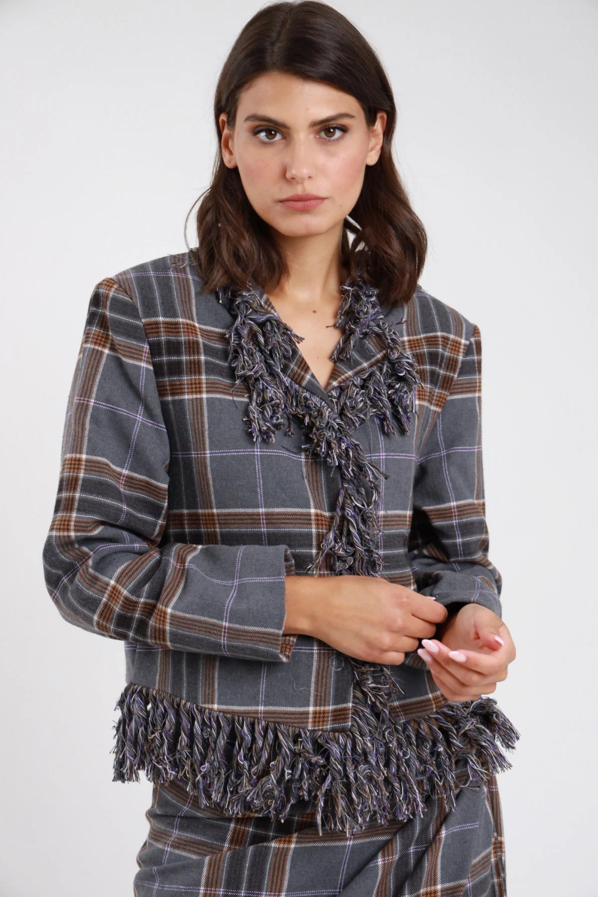 Giacca check tartan grigio antracite marrone donna boxy cropped frange multifilo bordo V fondo spalle padded scollo V aperta - vista frontale intera mani incrociate con gonna check coordinata