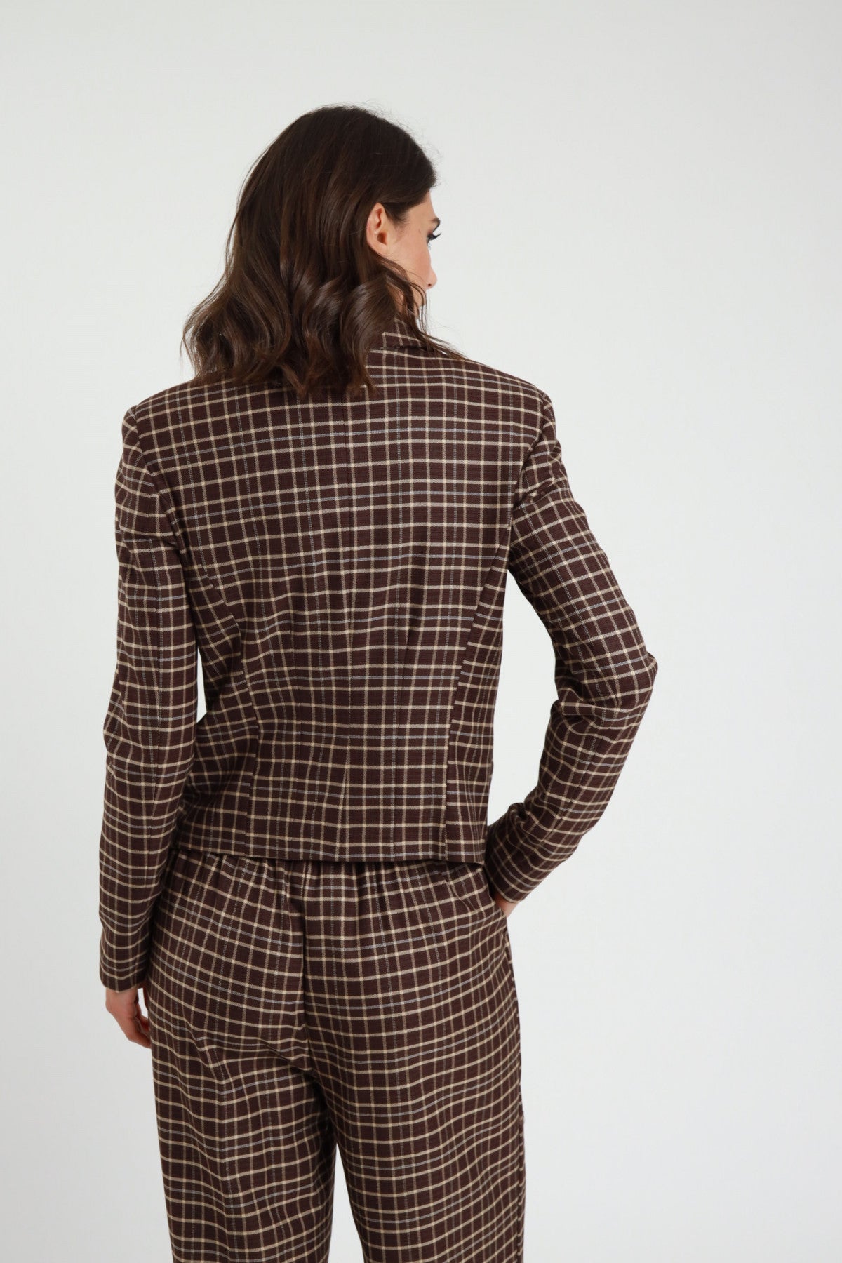 Blazer Corto Check tartan marrone cioccolato quadri panna revers V 2 bottoni tasche filetto patta spalle strutturate retro intera mano fianco - modella retro intera mano fianco sguardo laterale capelli castani scuri sfondo bianco pantalone check marrone