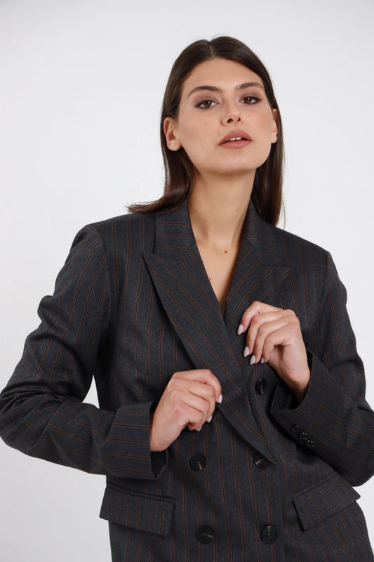 Blazer doppiopetto gessato Susy Mix Pre-Fall grigio antracite pinstripe bordeaux ruggine 64% poliestere viscosa elastan doppiopetto 6 bottoni scuri revers lancia ampio busto 3/4 mani bottoni sguardo alto - modella busto 3/4 mani bottoni sguardo alto capelli scuri lisci sfondo bianco pantalone gessato coordinato stesso tessuto tailleur abbinato