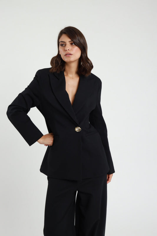 Blazer Punto Milano nero revers V profondo bottone dorato decorativo tasche filetto patta spalle strutturate frontale intera mano fianco - modella frontale intera mano fianco sguardo frontale capelli castani scuri sfondo bianco pantalone uovo nero kitten heel neri
