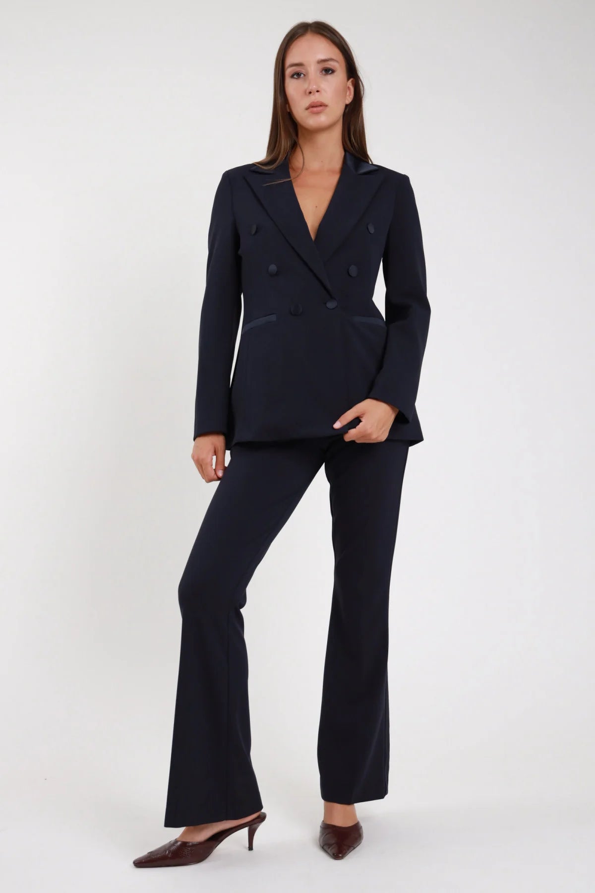 Completo tailleur blazer doppio petto blu navy raso pantalone flare - modella frontale intera mano in tasca sguardo frontale mules marrone capelli castani lisci