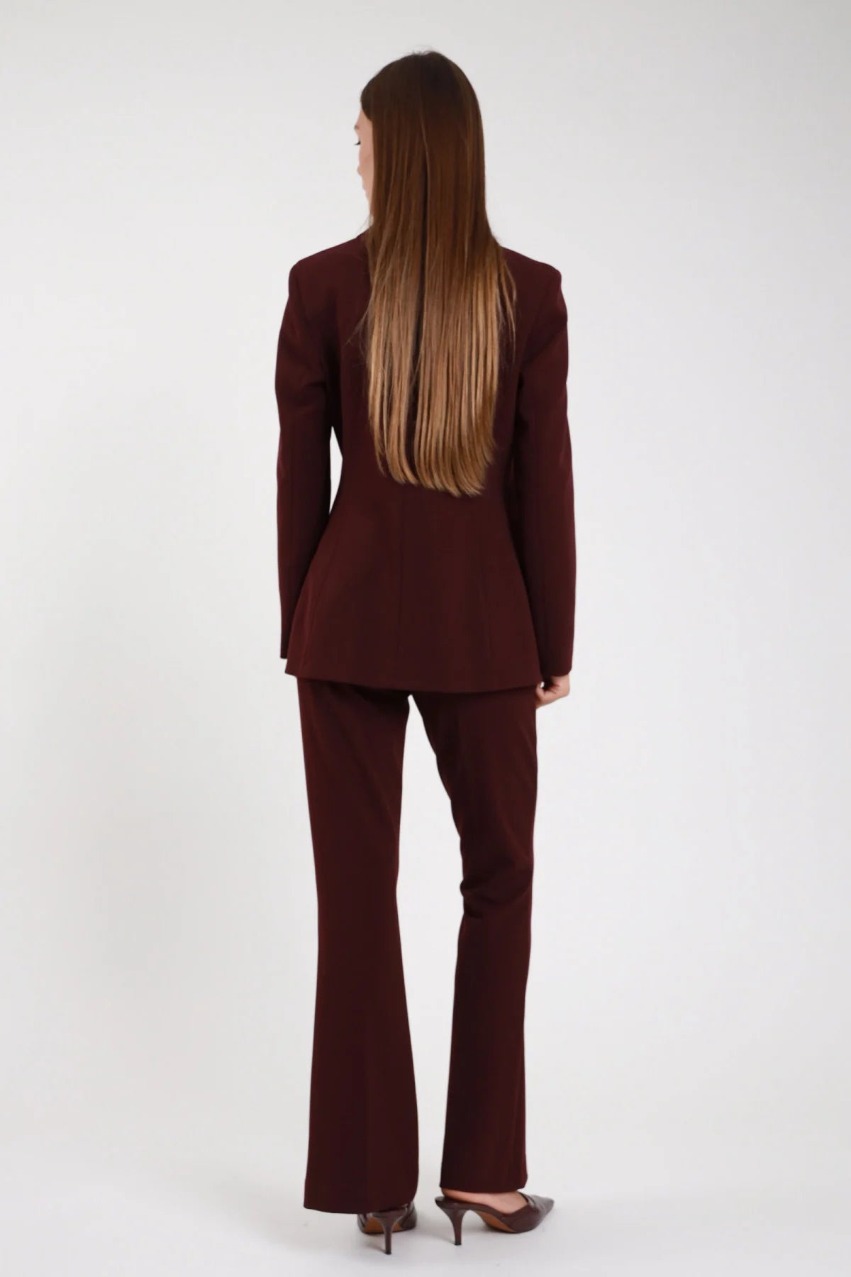 Completo tailleur bordeaux amaranto blazer doppio petto pantalone flare retro - modella retro intera capelli lunghi lisci castani mules marroni sguardo di lato