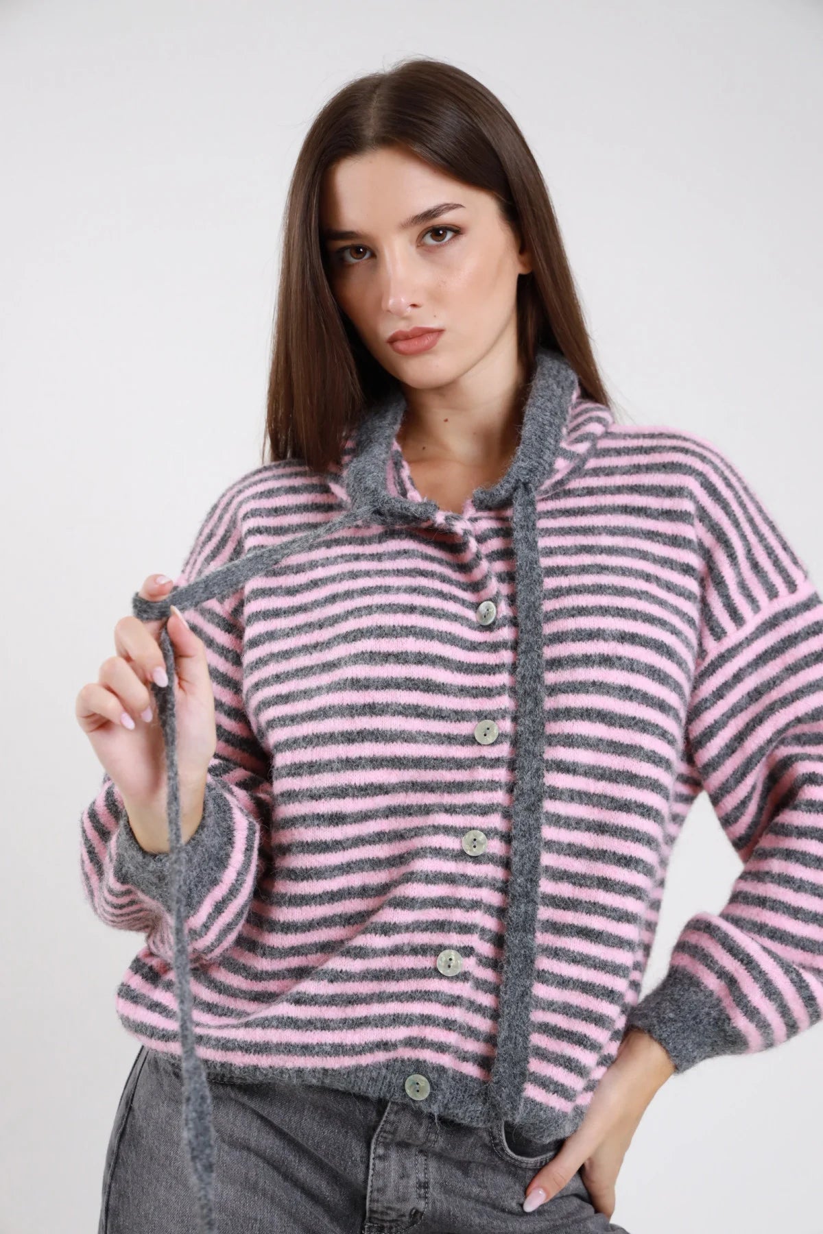 Felpa cardigan maglia bouclé eyelash righe bold bicolor rosa cipria grigio antracite cappuccio cordoncino bottoni madreperlati batwing oversize boxy frontale busto mano cordoncino - modella frontale busto mano cordoncino sguardo frontale capelli castani scuri lisci sfondo bianco jeans grigio