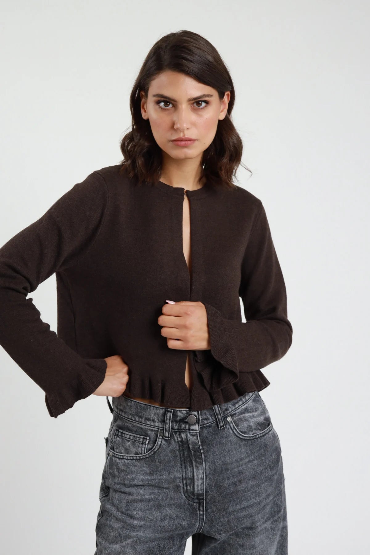 Giacchino gale maglia boucle rosa cipria malva frontale busto mani apertura girocollo manica lunga polsino volant balza ondulata orlo peplum crop jeans neri - modella frontale busto mani apertura sguardo frontale jeans neri capelli castani mossi