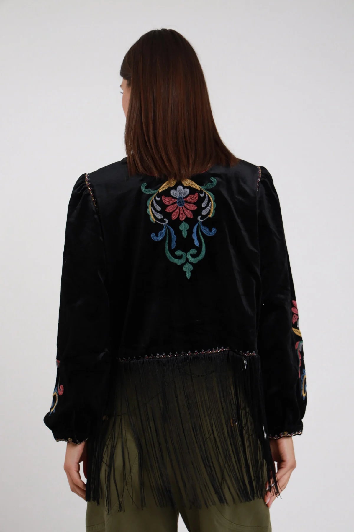 Giacchino Ricamato Frange nero velluto raso ricamo floreale folk multicolor grande centrato schiena fiore foglie colorate frange lunghe nere orlo retro bordi dorati cuciture retro intera schiena - modella retro intera sguardo dritto capelli castani scuri sfondo bianco pantaloni verde militare