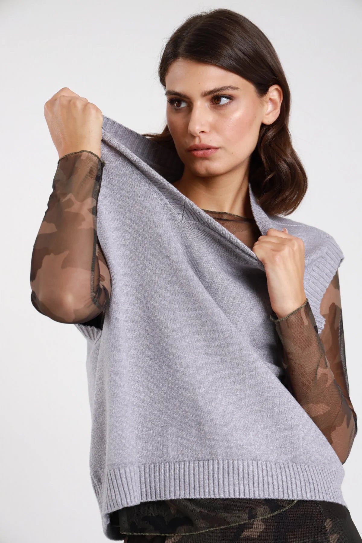 Gilet V maglia beige sabbia donna boxy cropped scollo V bordino costine cap-sleeve spalle dropped - vista frontale mezzo busto seduta mano al collo con pantaloni check