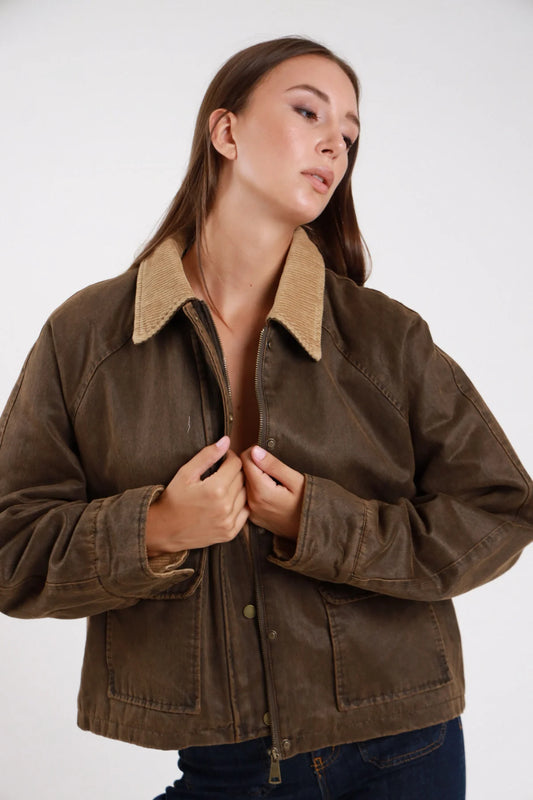 Giacca ecopelle cerata waxed verde khaki frontale busto mano colletto corduroy beige bottoni snap dorati tasche patch - modella frontale busto mano colletto sguardo frontale jeans indaco capelli castani lisci