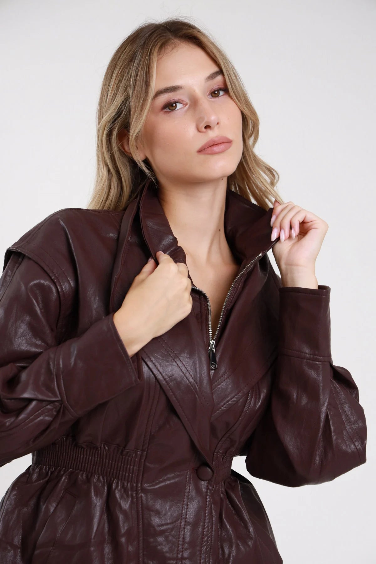 Giacca ecopelle bordeaux vino scuro colletto revers zip aperta - modella busto ravvicinato mani al colletto sguardo frontale capelli biondi mossi