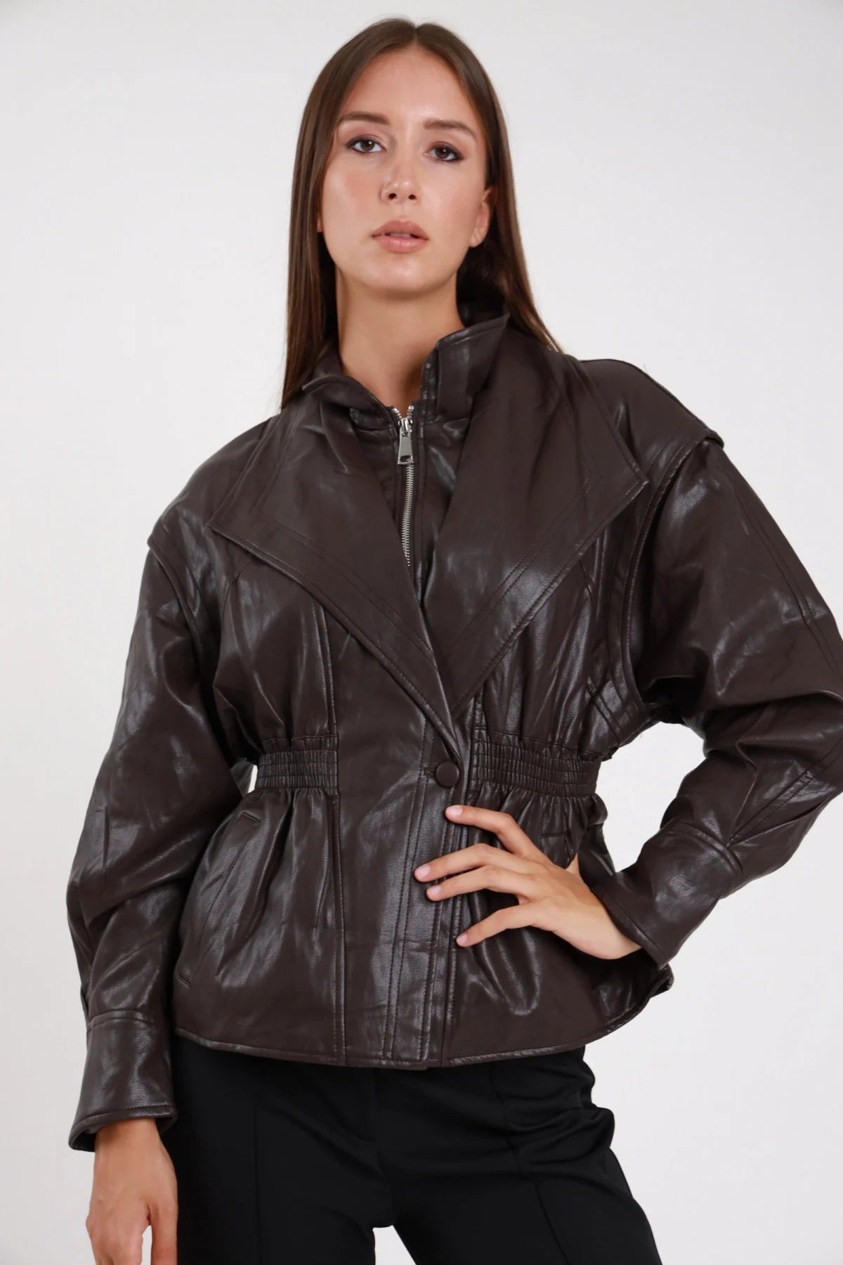 Giacca ecopelle marrone scuro cioccolato zip vita smock peplum - modella frontale intera mano sul fianco sguardo frontale pantaloni neri capelli castani lisci