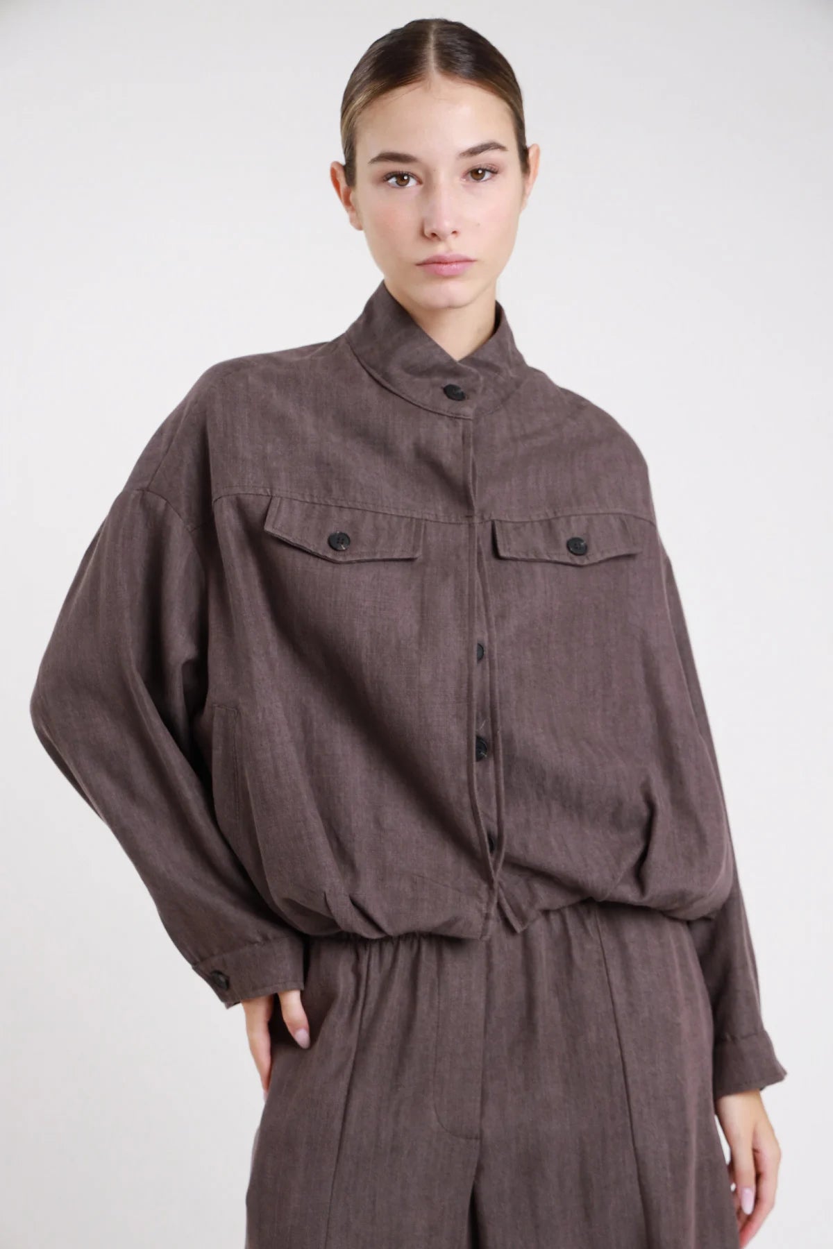Bomber oversize marrone cioccolato spina di pesce - modella busto frontale con pantaloni marroni coordinati e tasche pattina