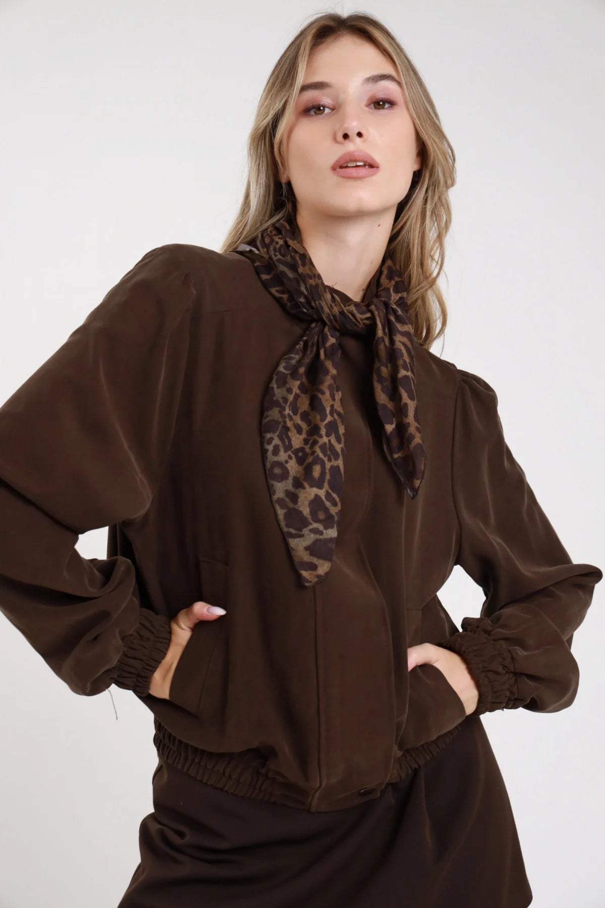 Giacca bomber viscosa suede verde militare oliva frontale tre quarti mano collo foulard animalier leopardato annodato collo alto snap champagne manica puff - modella frontale tre quarti mano collo foulard leopard sguardo laterale pantaloni cioccolato capelli castani raccolti