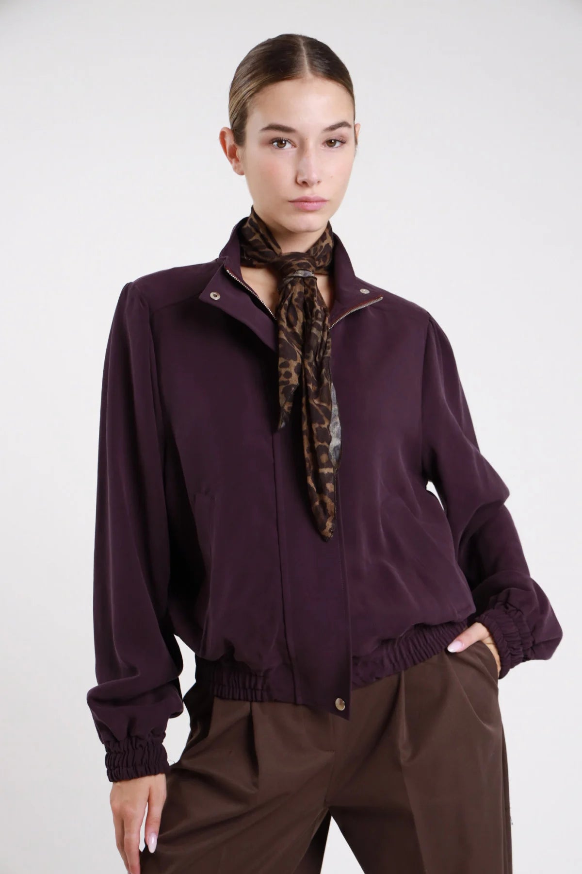 Giacca bomber viscosa suede cioccolato moro retro intera manica puff polsino elasticizzato arricciato orlo elastico vita crop - modella retro intera mano fianco sguardo basso pantaloni cioccolato capelli biondi mossi