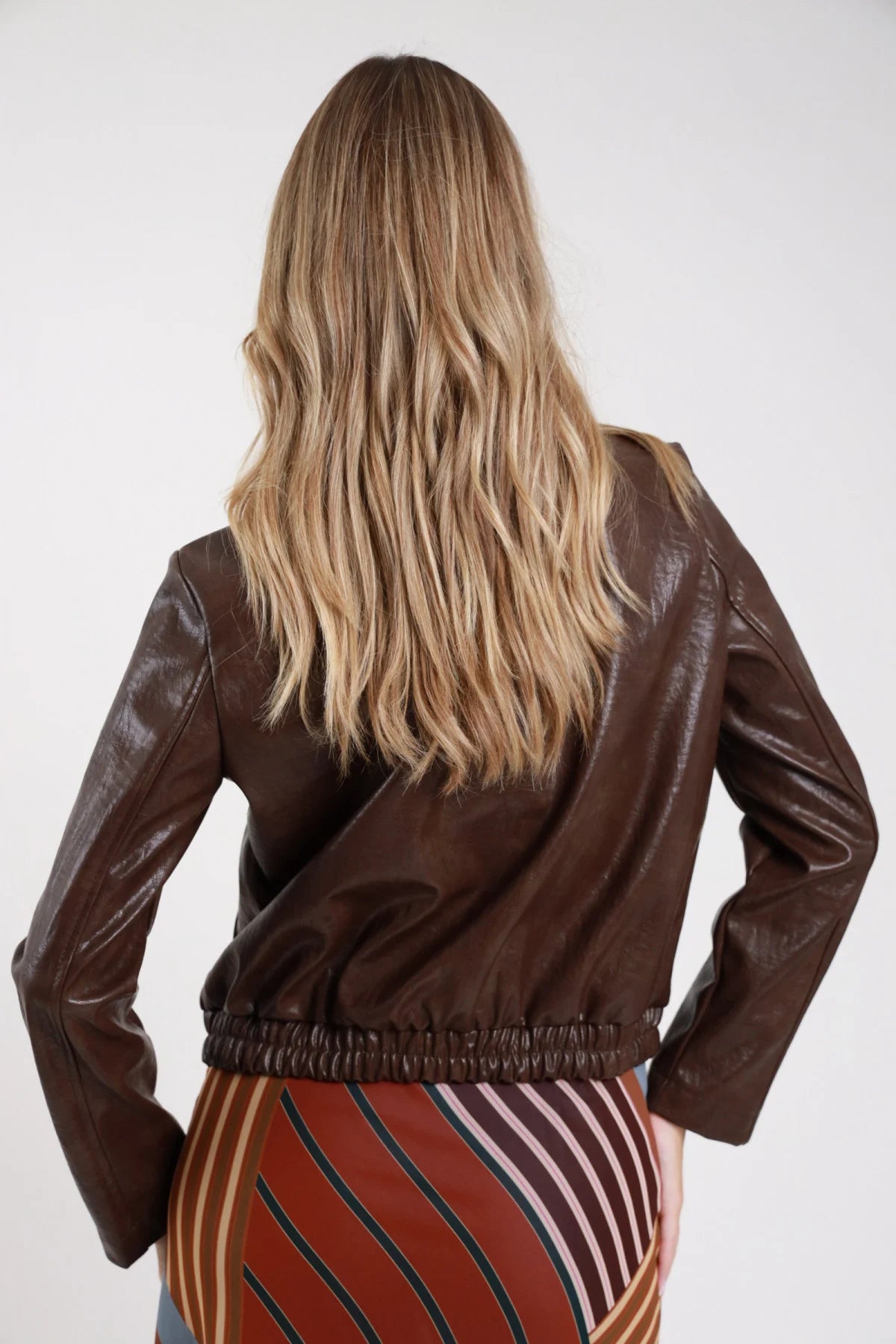 Bomber ecopelle verde oliva khaki frontale busto collo alto bottoni tasche patch cargo - modella busto frontale mani ai fianchi sguardo frontale capelli castani lisci gonna nera