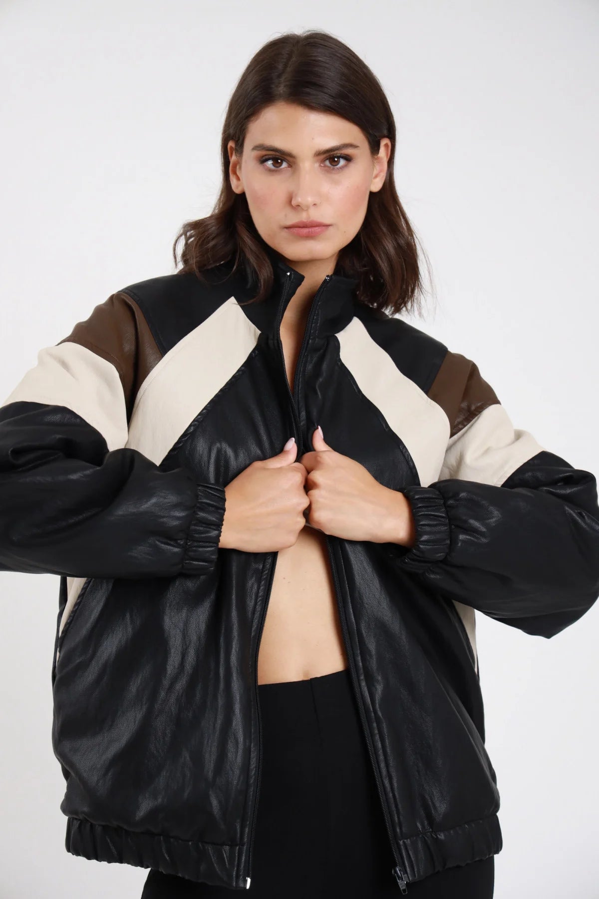 Giacca ecopelle bomber oversize nero donna inserti color-block panna beige marrone cioccolato spalle maniche collo alto zip polsini costine - dettaglio frontale mezzo busto giacca aperta mani sul petto
