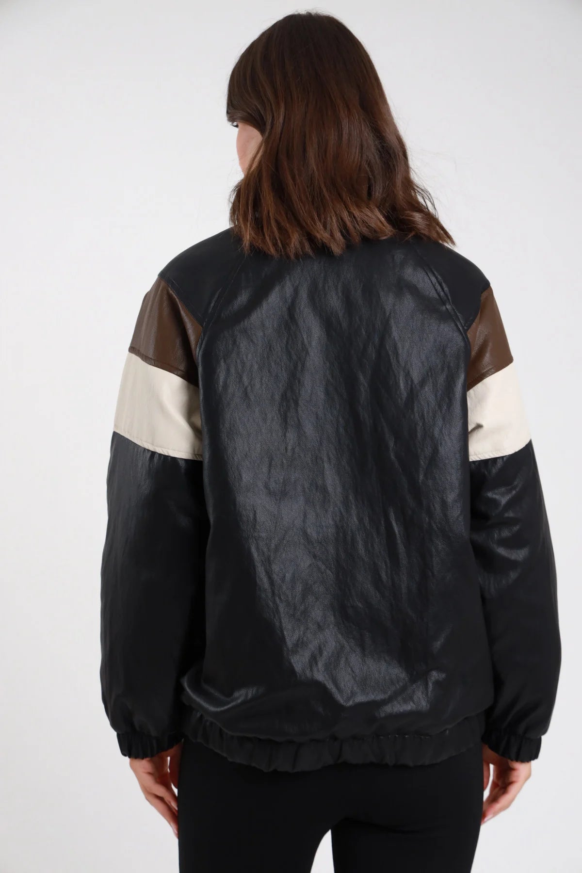 Giacca ecopelle bomber oversize nero donna inserti color-block panna beige marrone spalle maniche polsini costine fascia elastica - vista posteriore intera con leggings neri